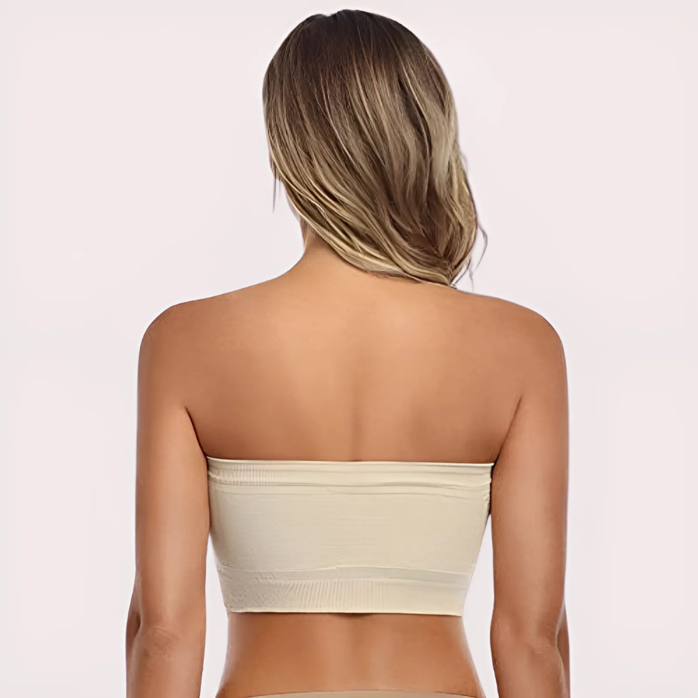 Woman wearing a beige strapless top on a light pink background