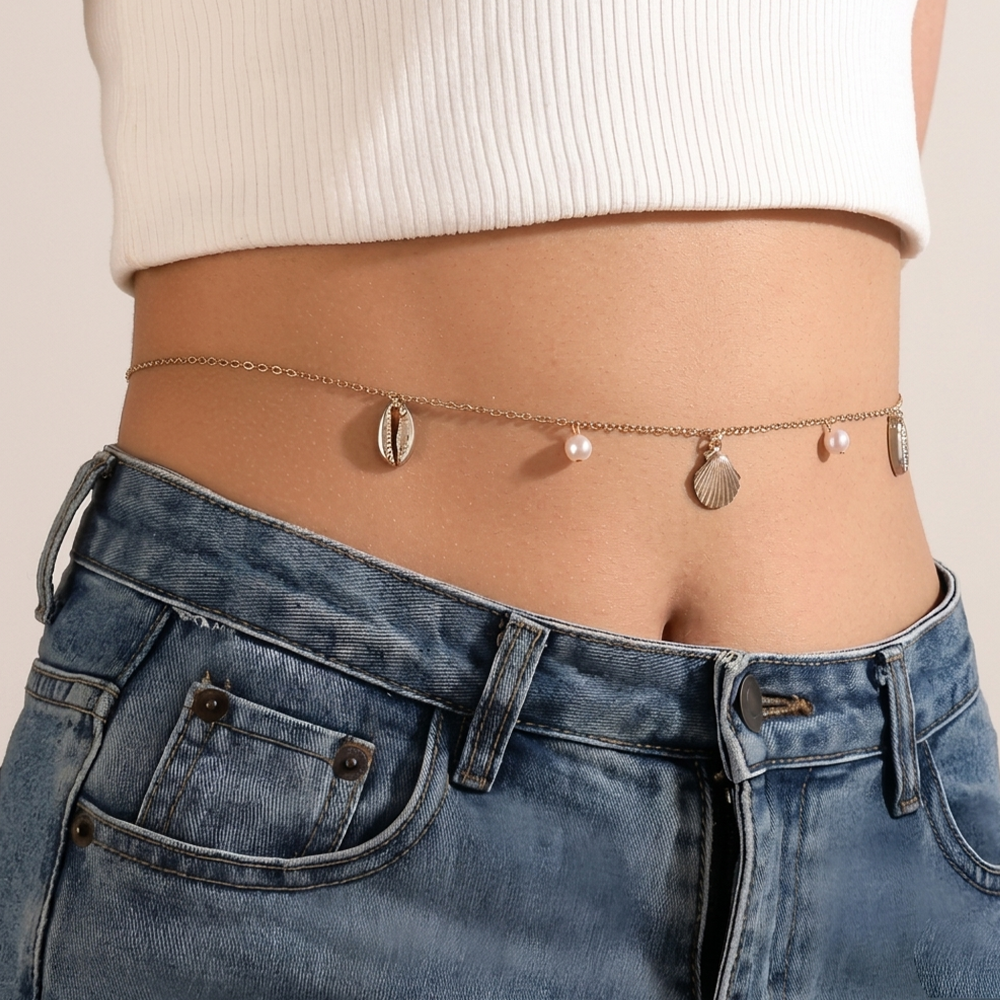 Person wearing a gold chain belt with shell and pearl charms 