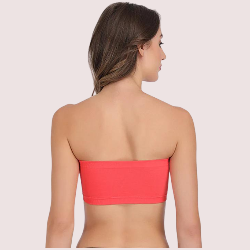 Woman wearing a coral strapless top against a light pink background