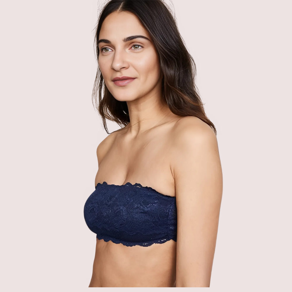 Woman wearing a navy blue strapless lace bra against a light pink background