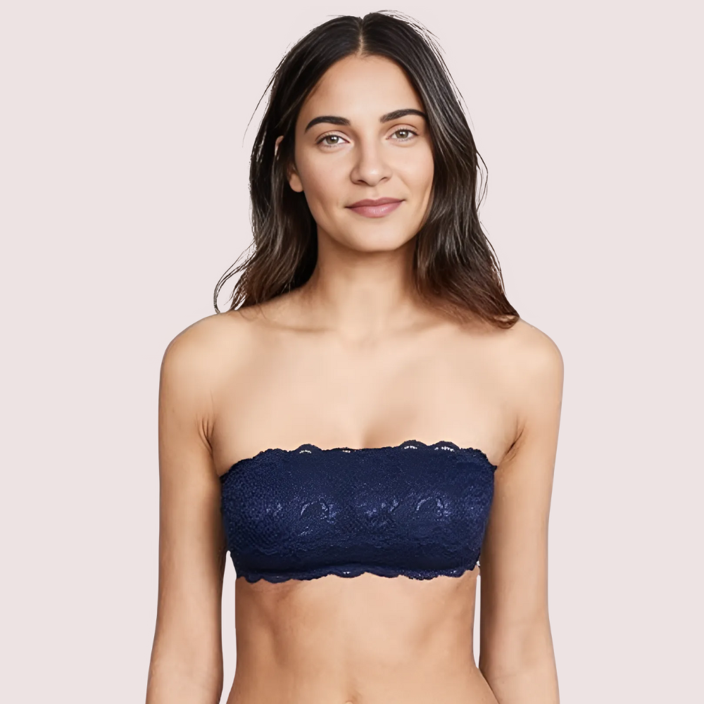 Woman wearing a navy blue strapless lace top against a light pink background
