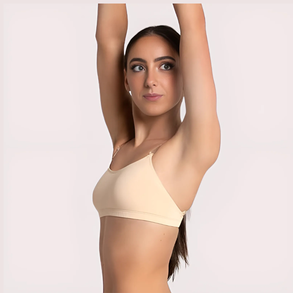 Woman wearing a beige sports bra with arms raised against a plain background