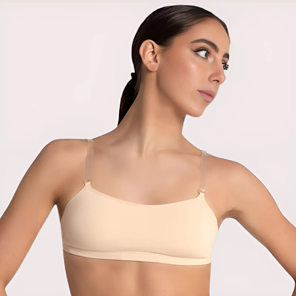 Woman wearing a beige bralette against a plain background