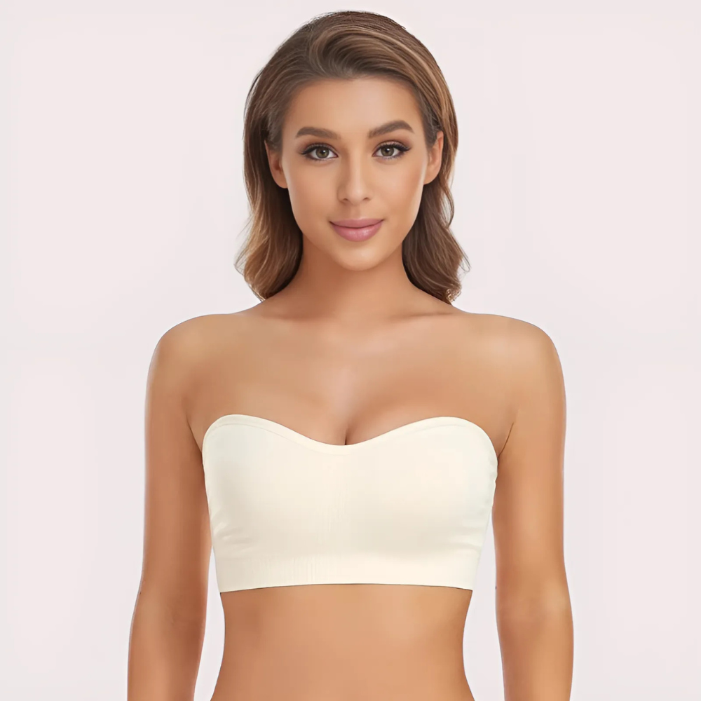 Woman wearing a strapless white top against a plain background