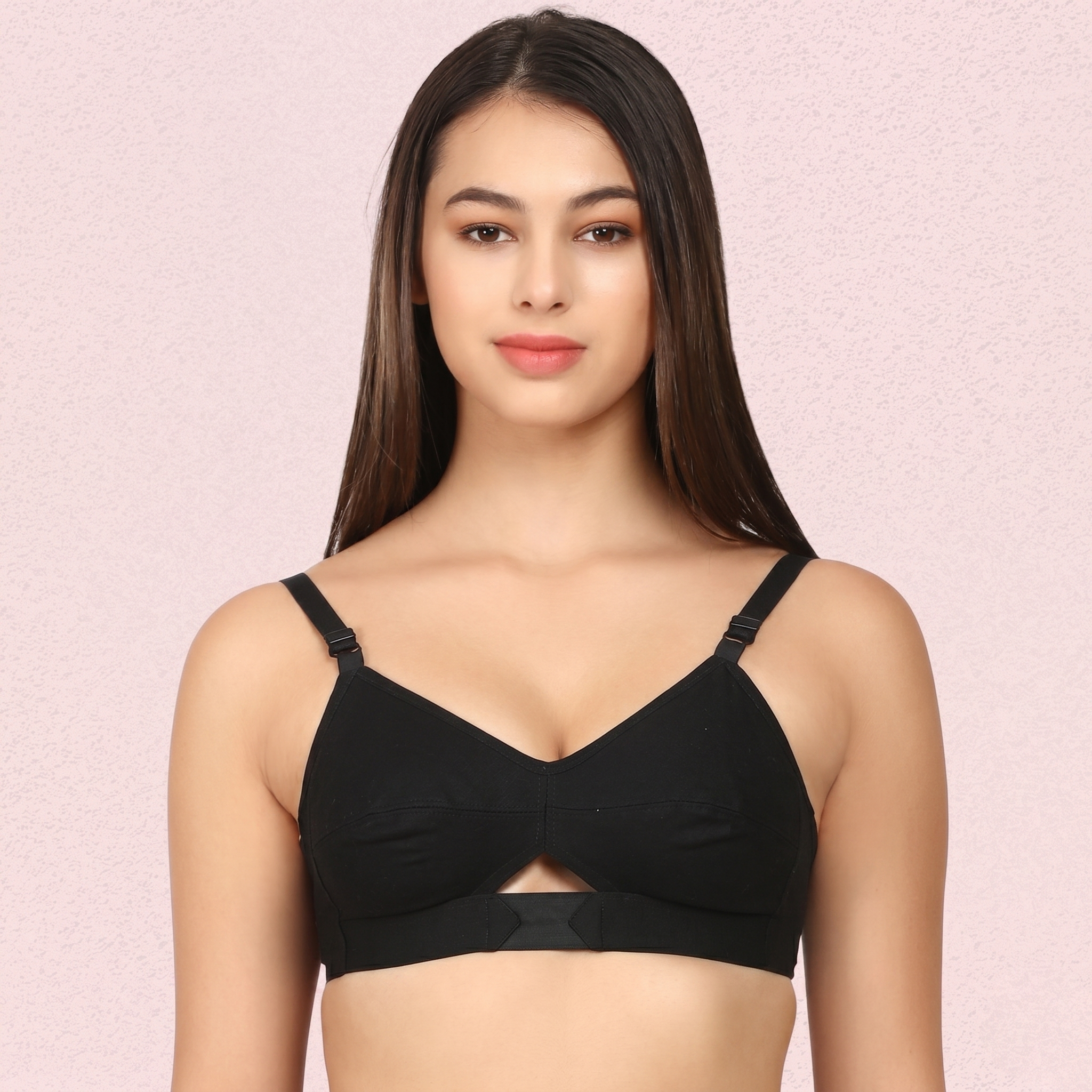 Woman wearing a black bralette against a pink background