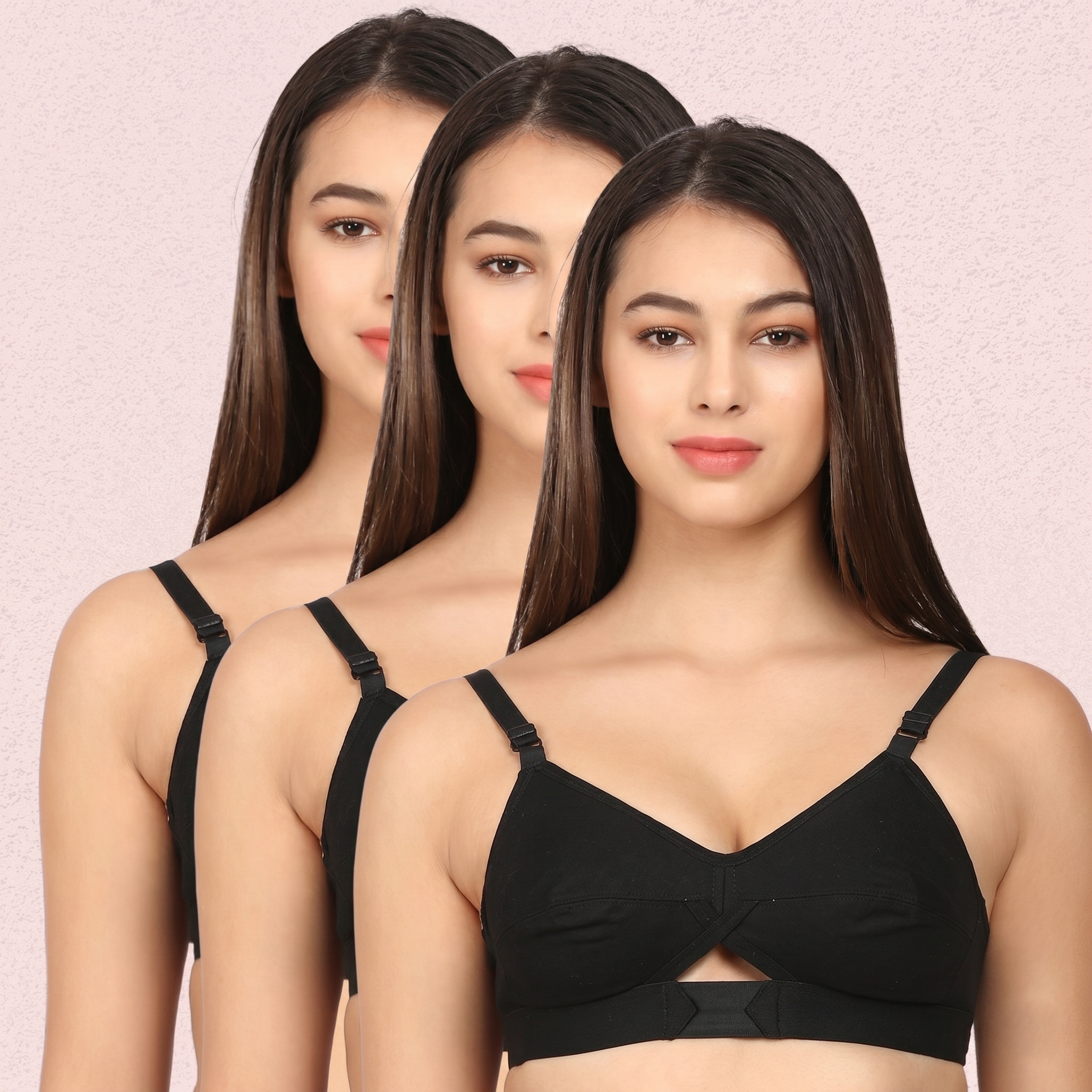 Three women wearing black bras against a pink background