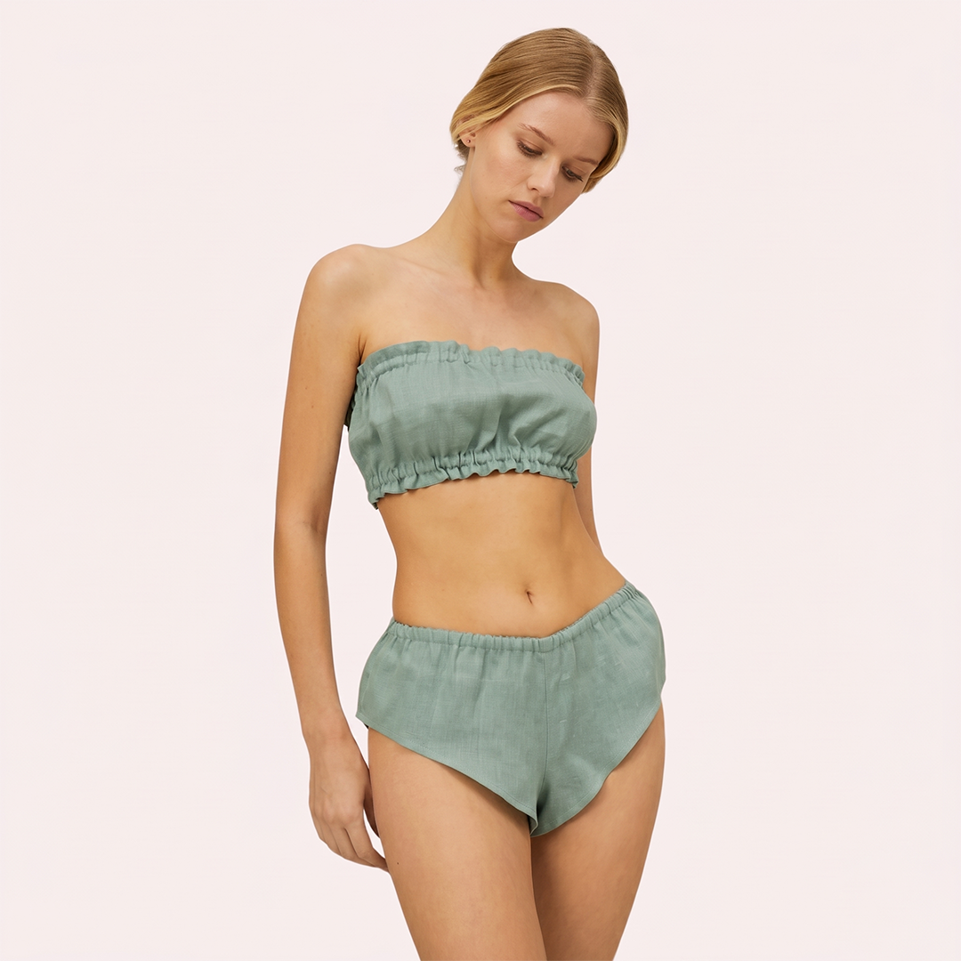 Woman wearing a green strapless bikini set on a light pink background