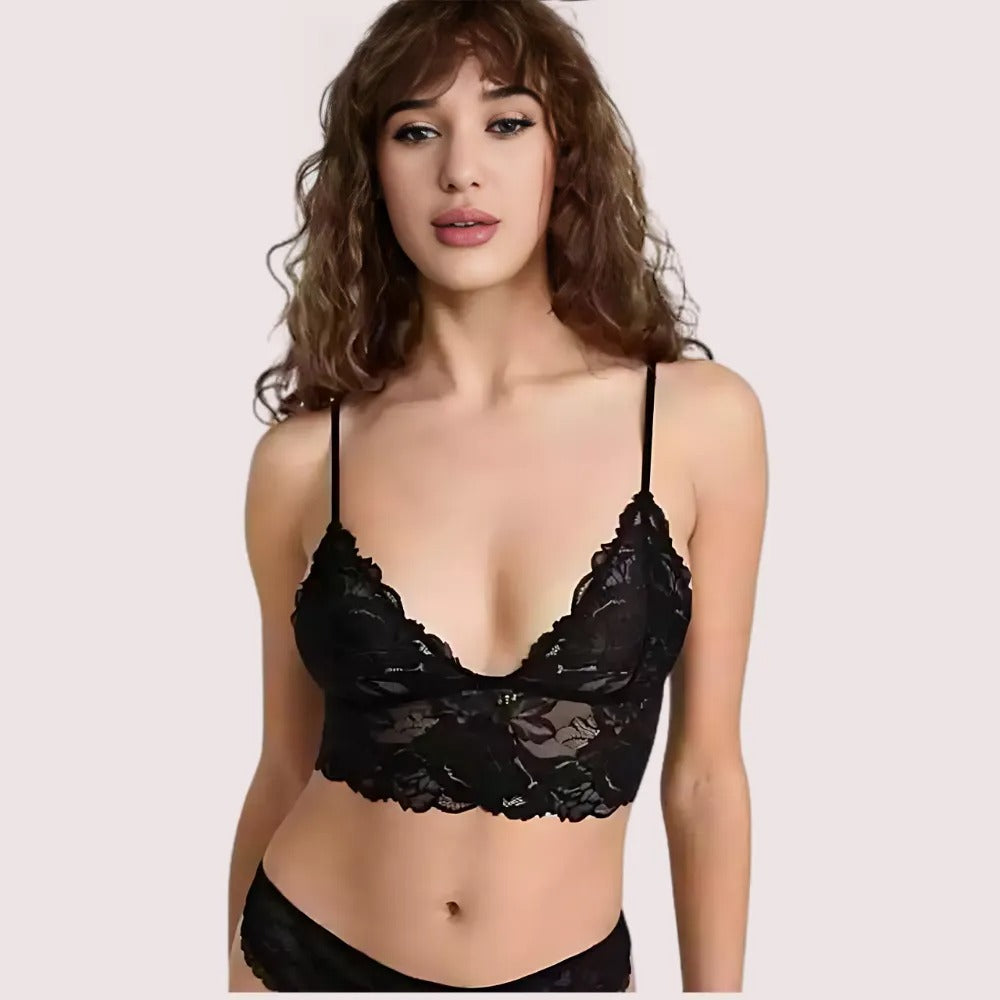 Woman wearing a black lace bralette on a plain background