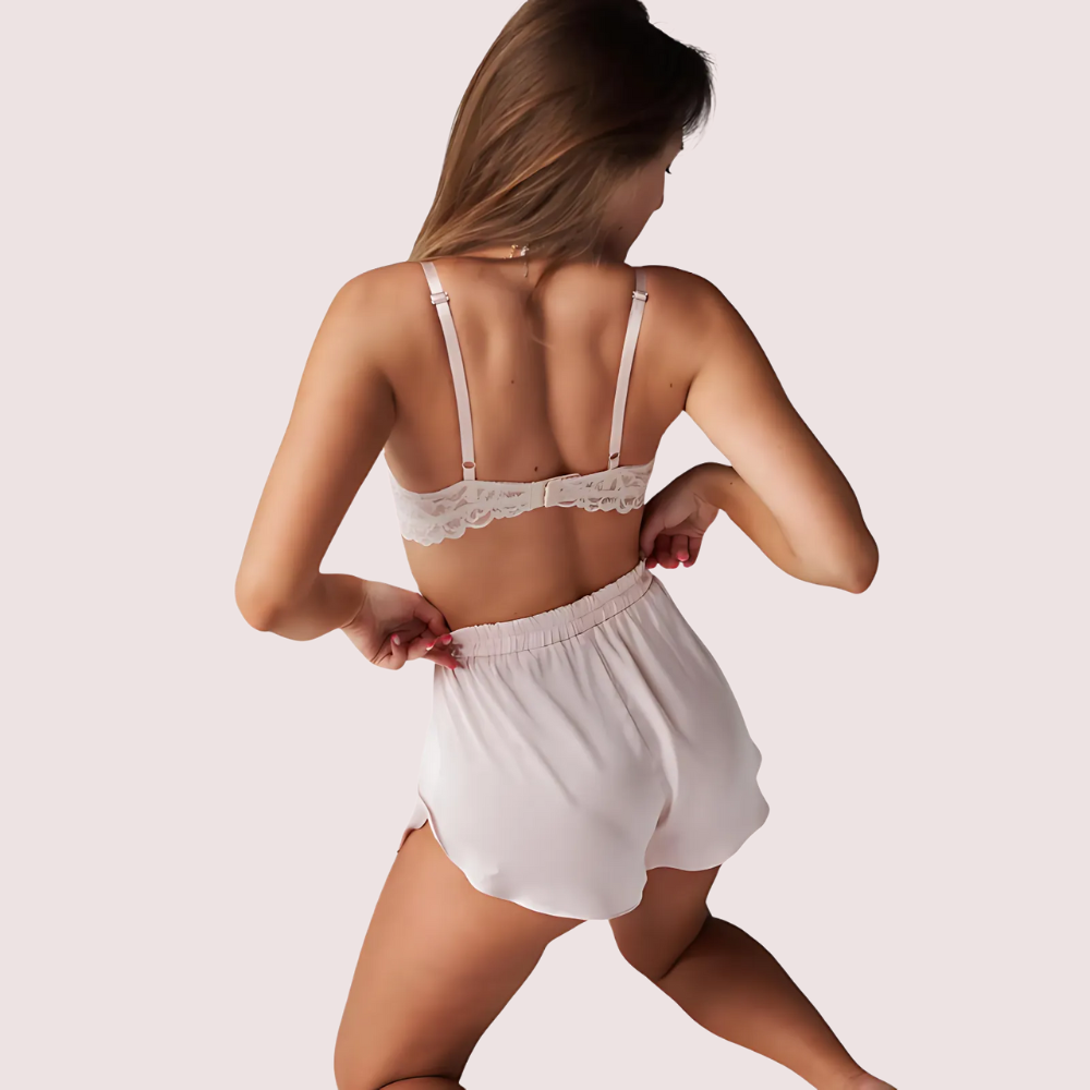 Woman wearing a white lace bra and shorts on a plain background