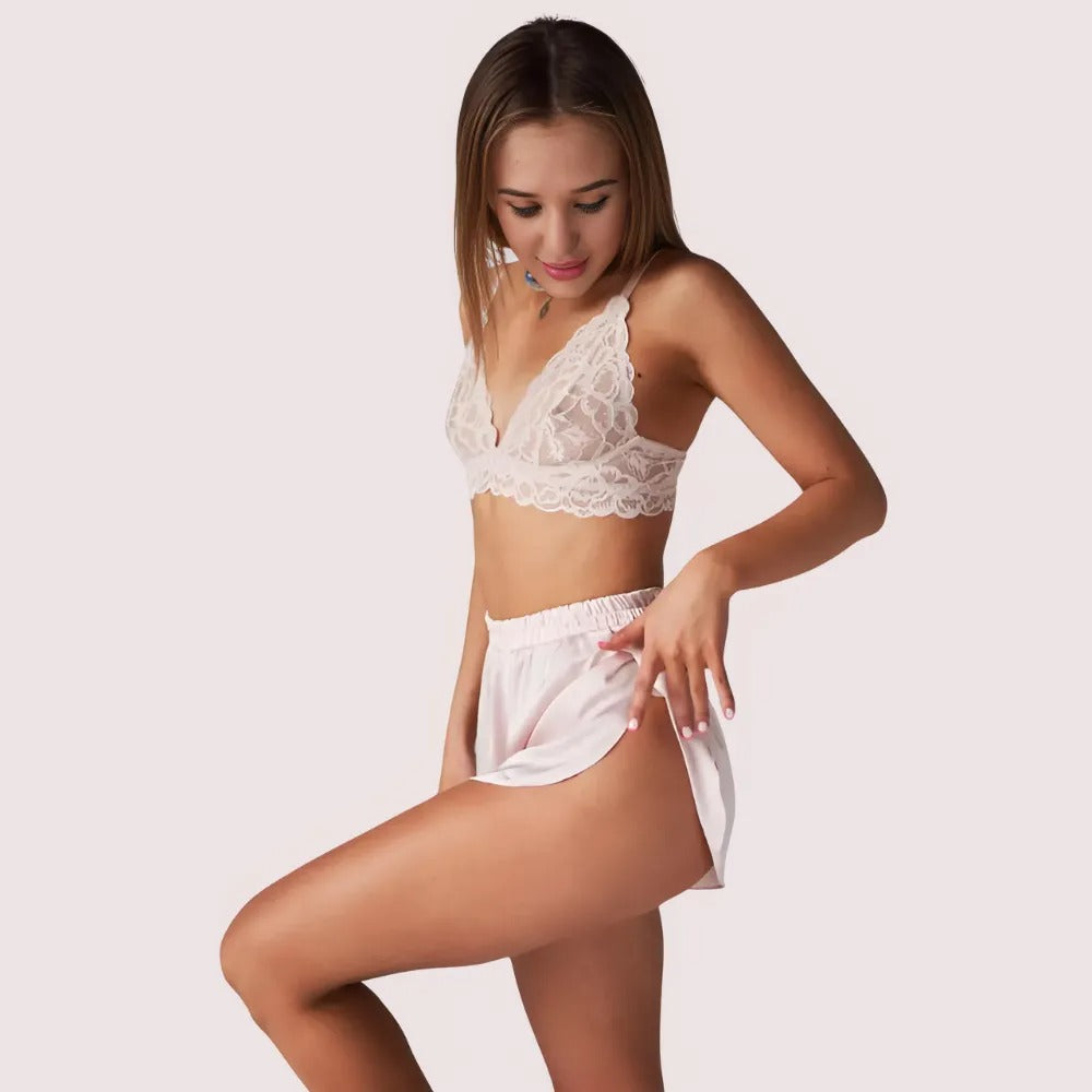 Woman wearing a white lace bralette and shorts on a plain background