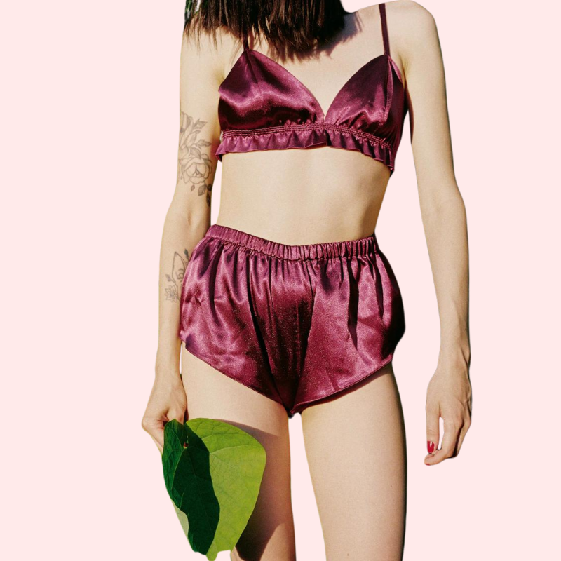 Person wearing a burgundy satin outfit with a plain background