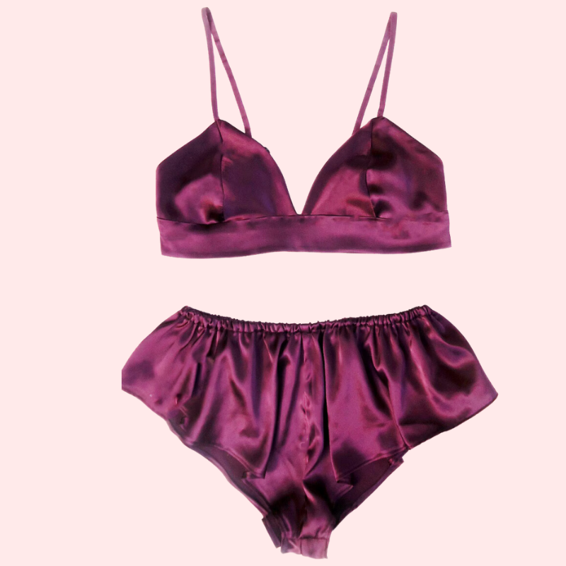 Purple satin bralette and shorts set on a light pink background