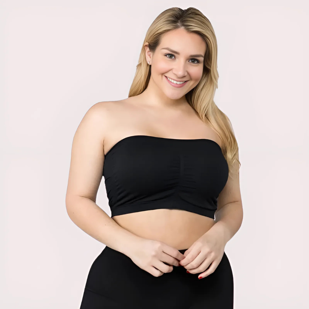 Woman wearing a black strapless top against a light pink background