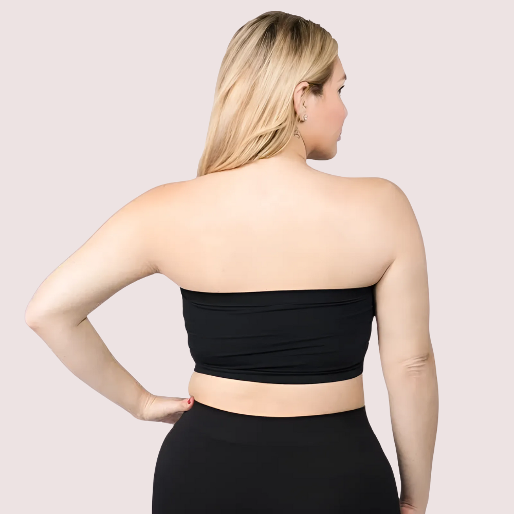 Woman wearing a black strapless top and black pants on a light pink background