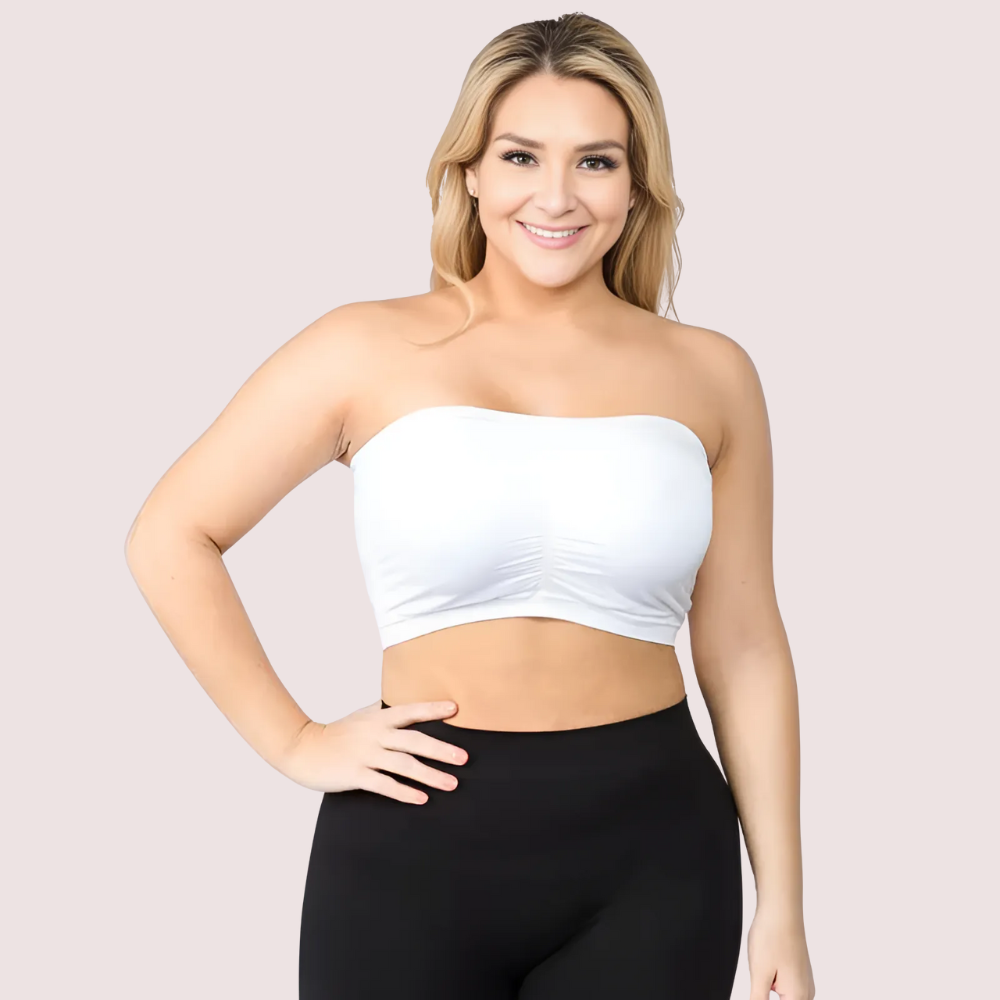 Woman wearing a white strapless top and black leggings on a light pink background