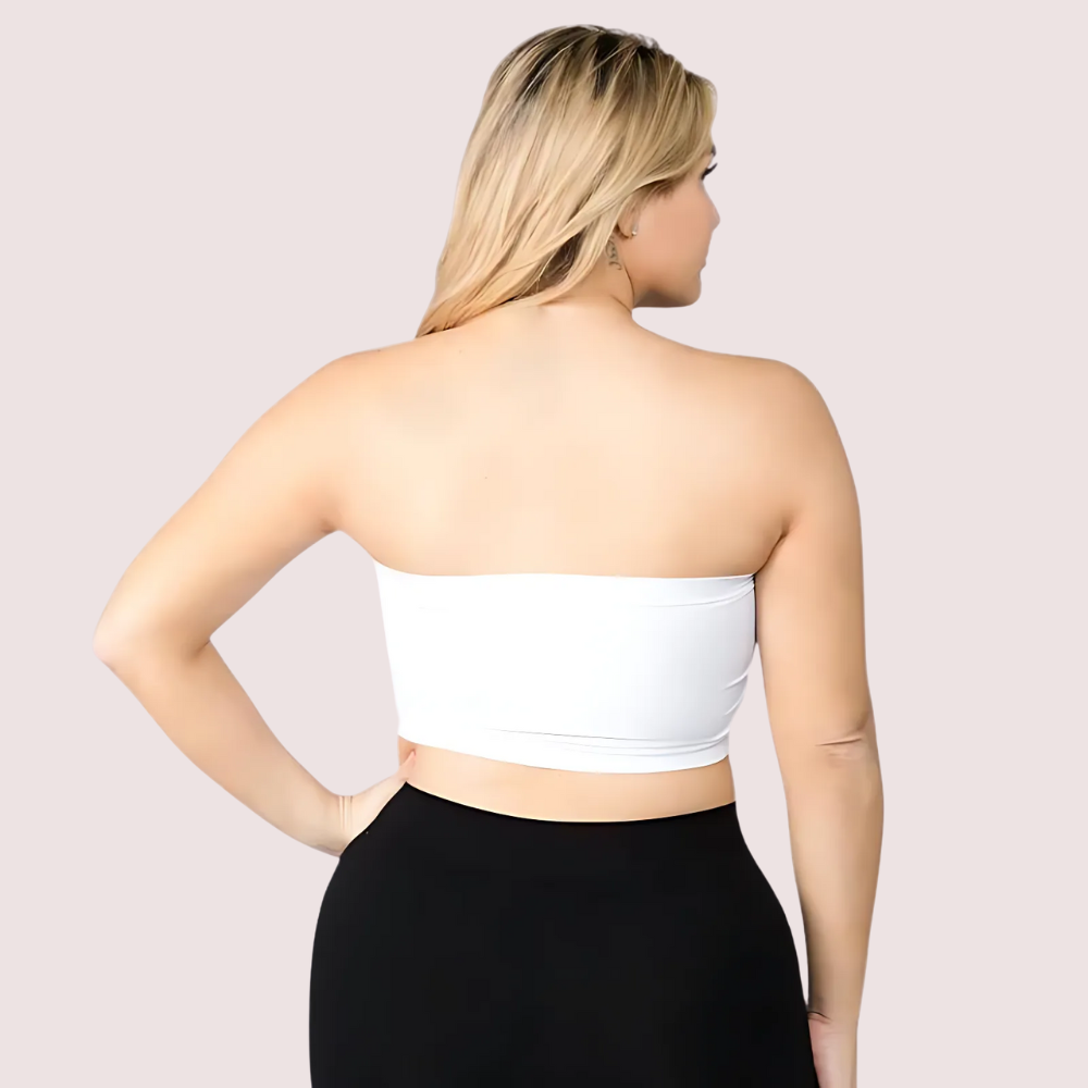 Woman wearing a white strapless top and black pants on a light pink background