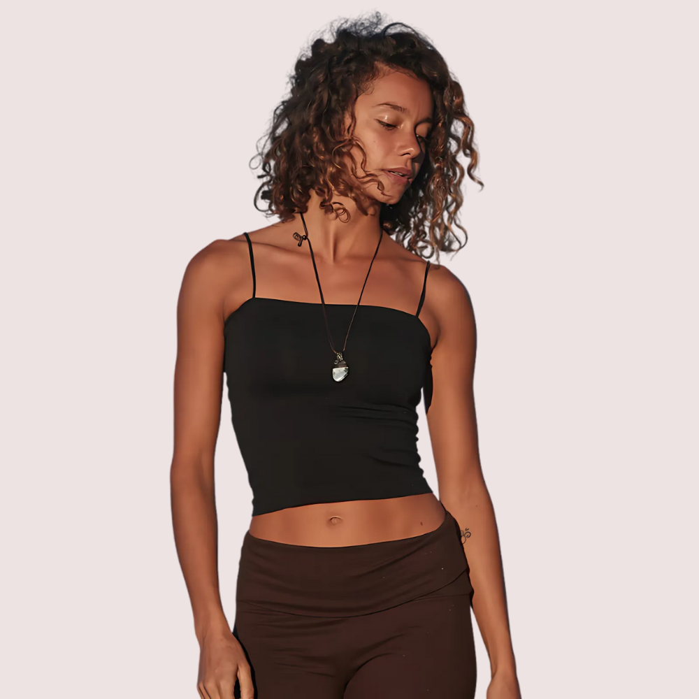 Woman wearing a black tank top and brown pants on a plain background