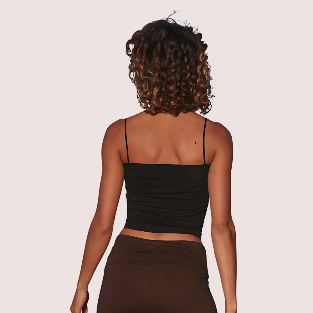 Woman wearing a black top and brown skirt on a light pink background