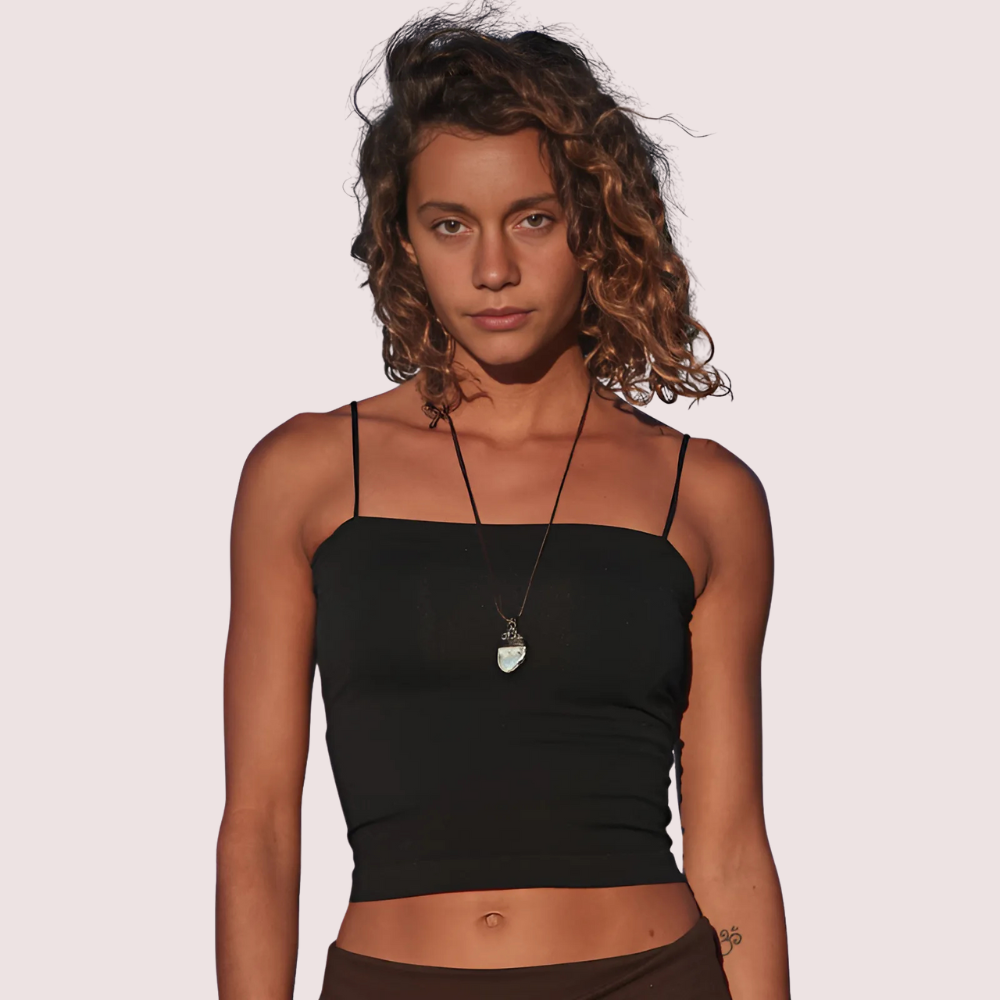 Woman wearing a black tank top with a plain background