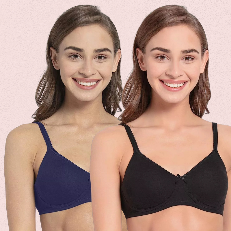 Two women wearing blue and black bras against a pink background