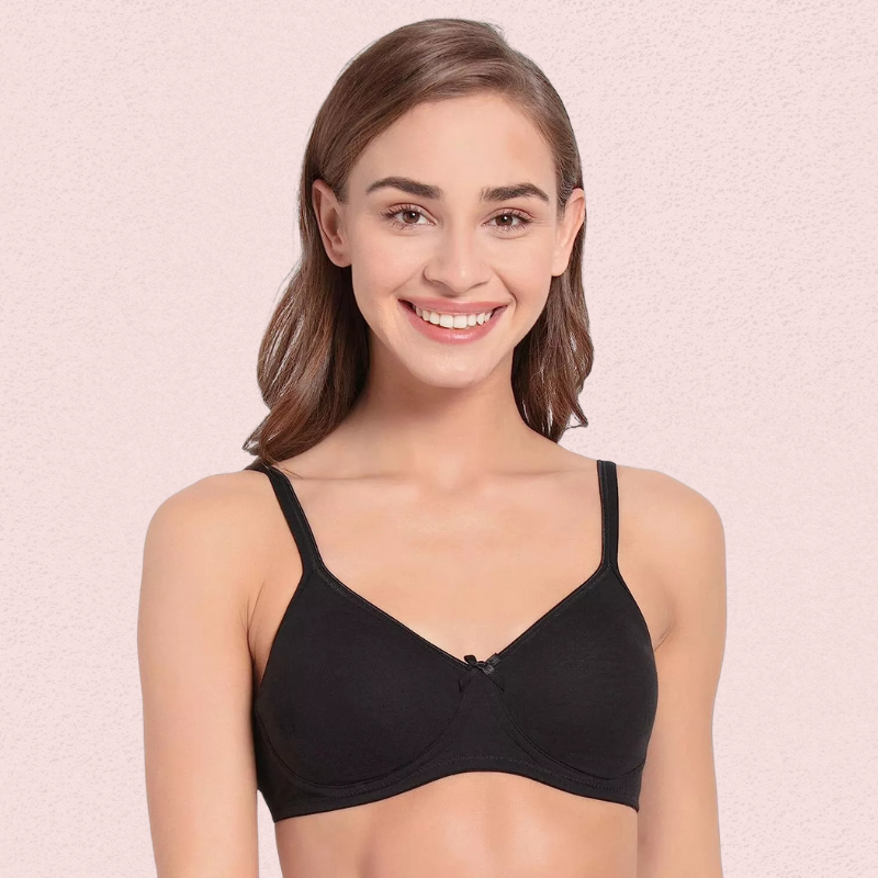 Woman wearing a black bra against a pink background