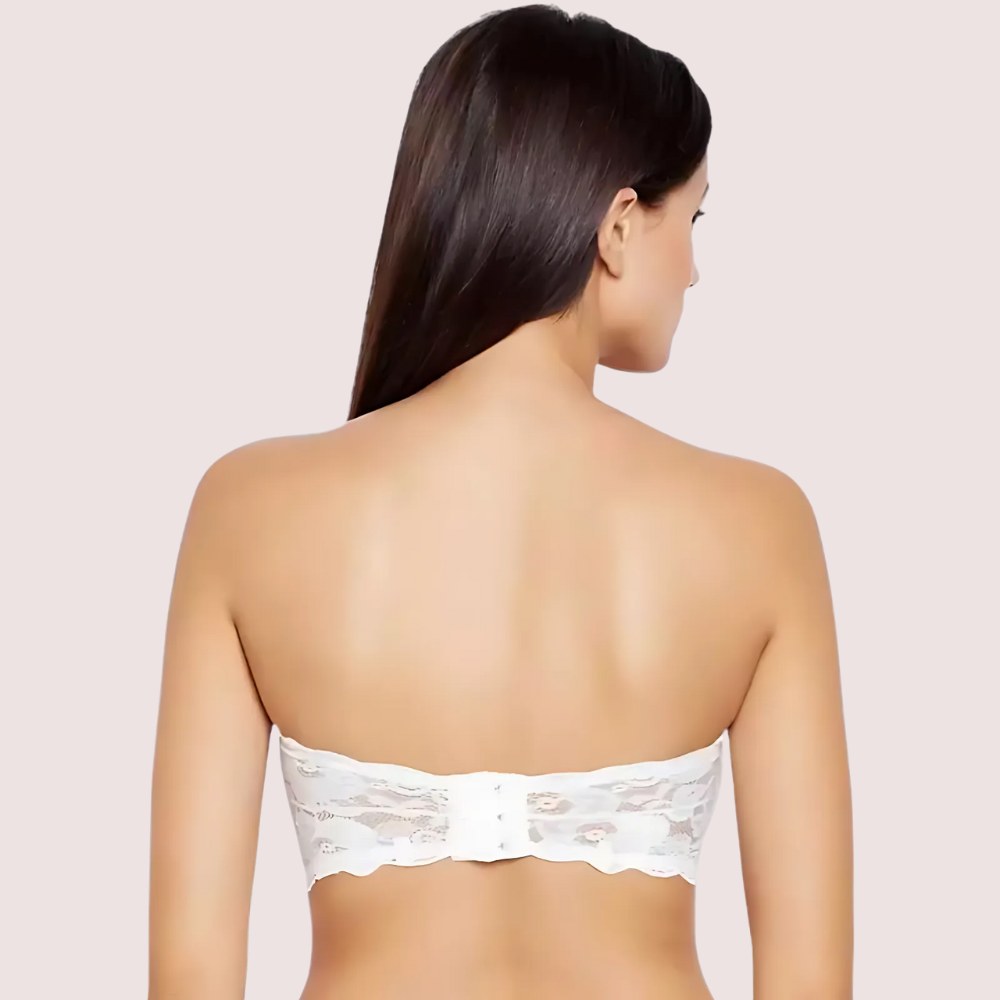 Woman wearing a white lace strapless top against a light pink background
