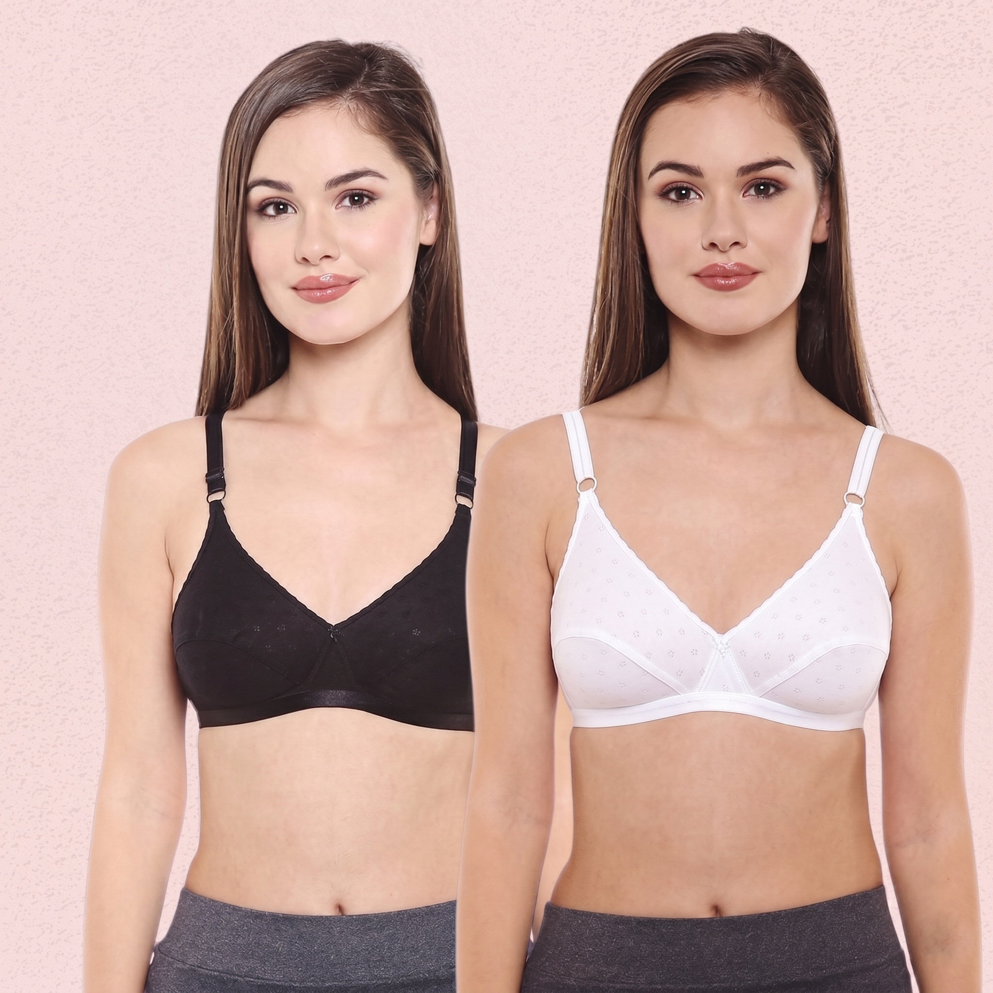 Two women wearing black and white bras against a pink background