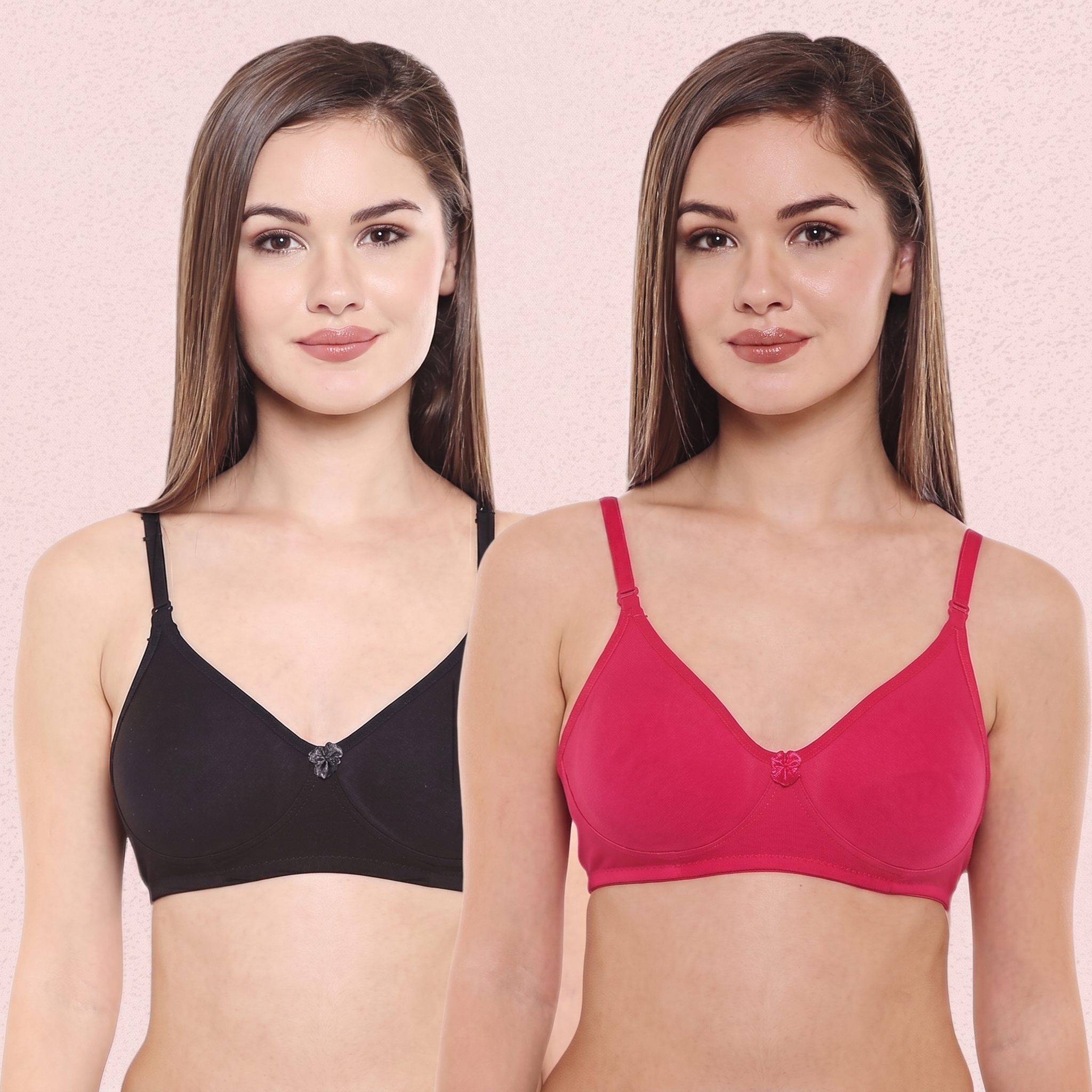 Two women wearing black and pink bras against a pink background