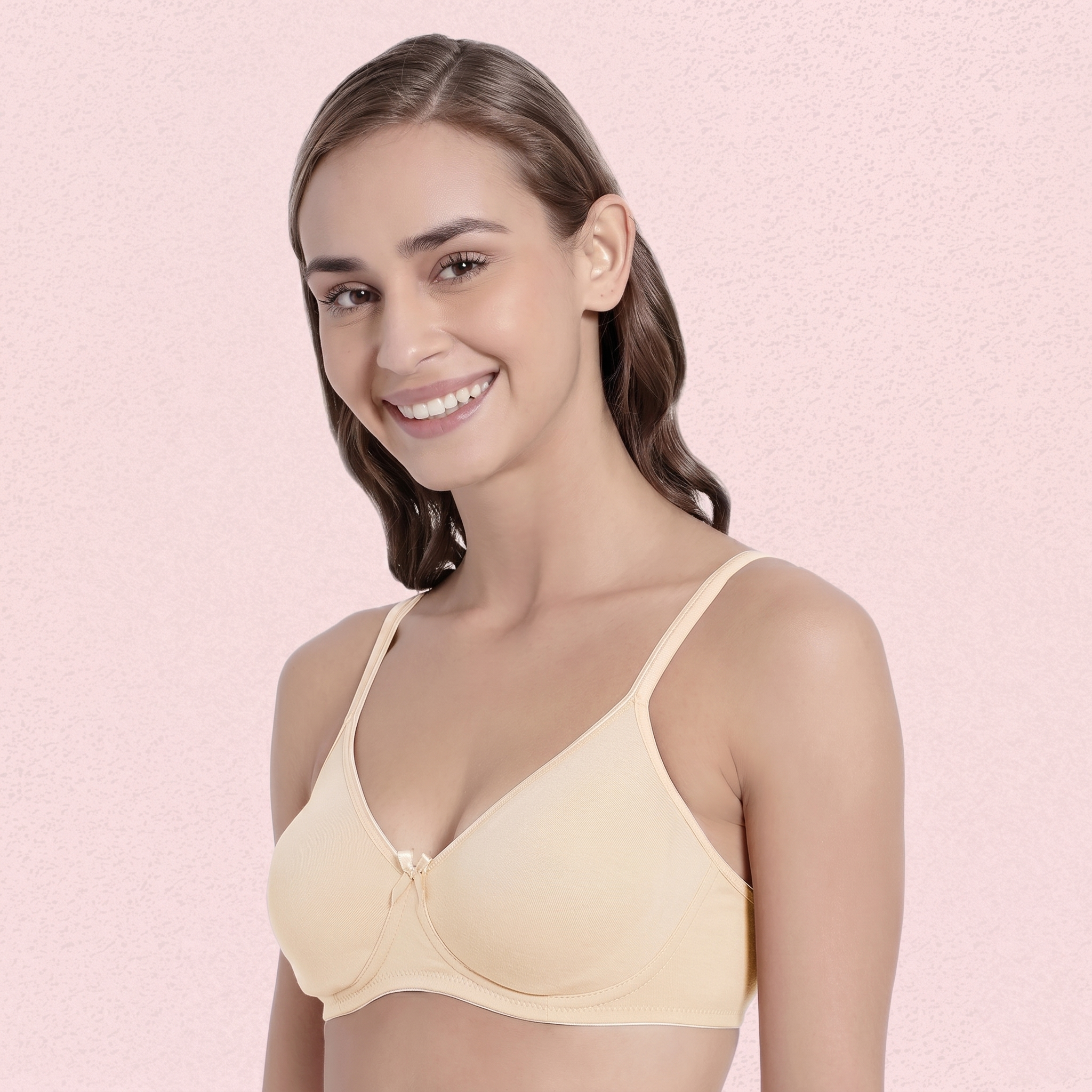 Woman wearing a beige bra against a pink background