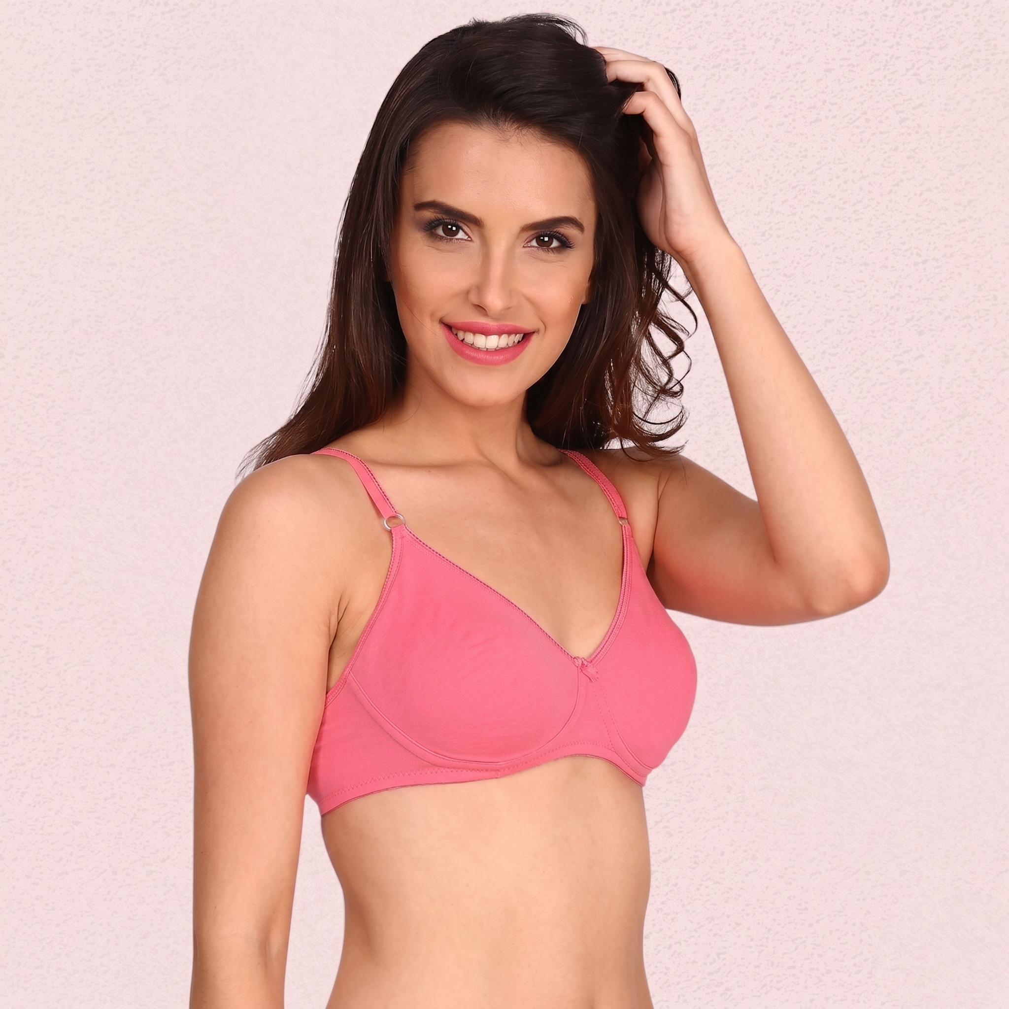 Woman wearing a pink bra against a light pink background
