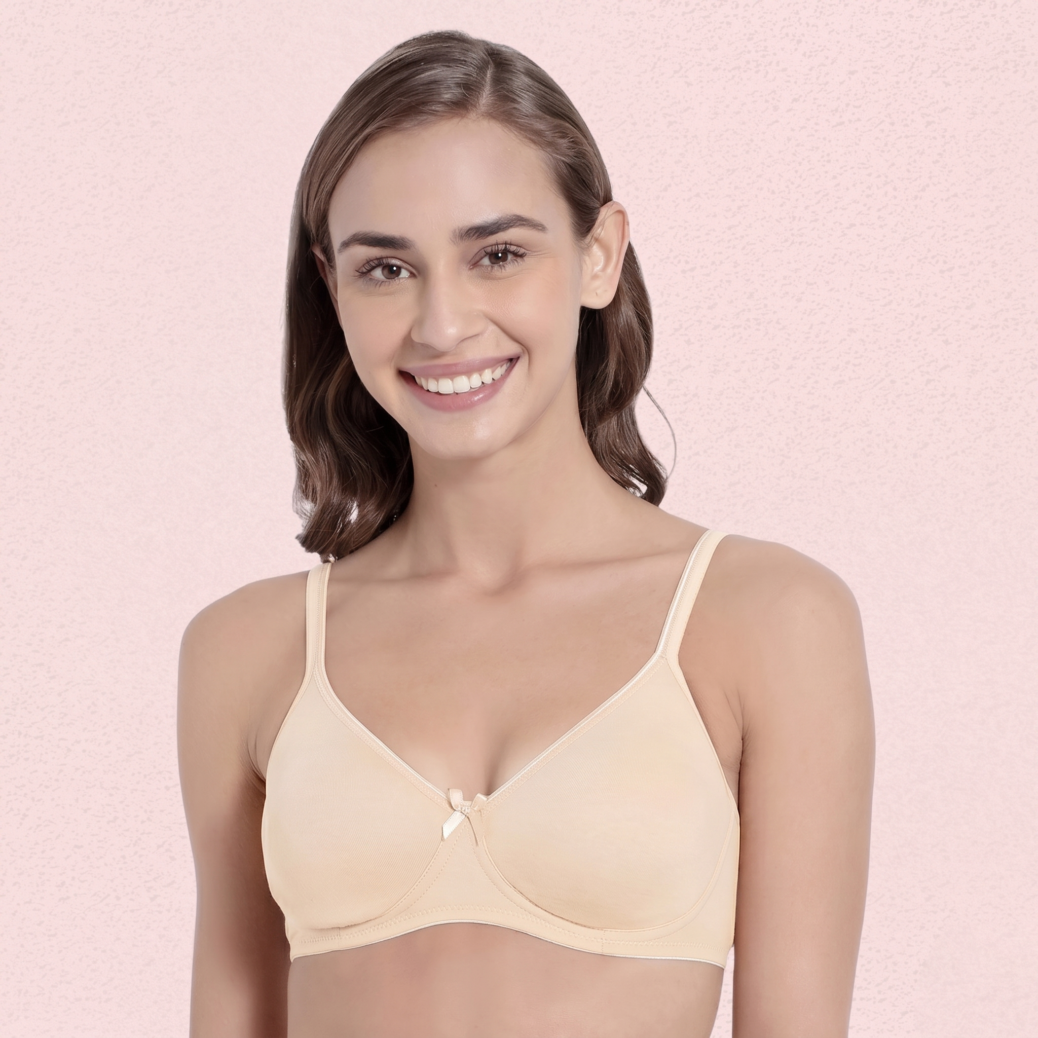 Woman wearing a beige bra against a pink background