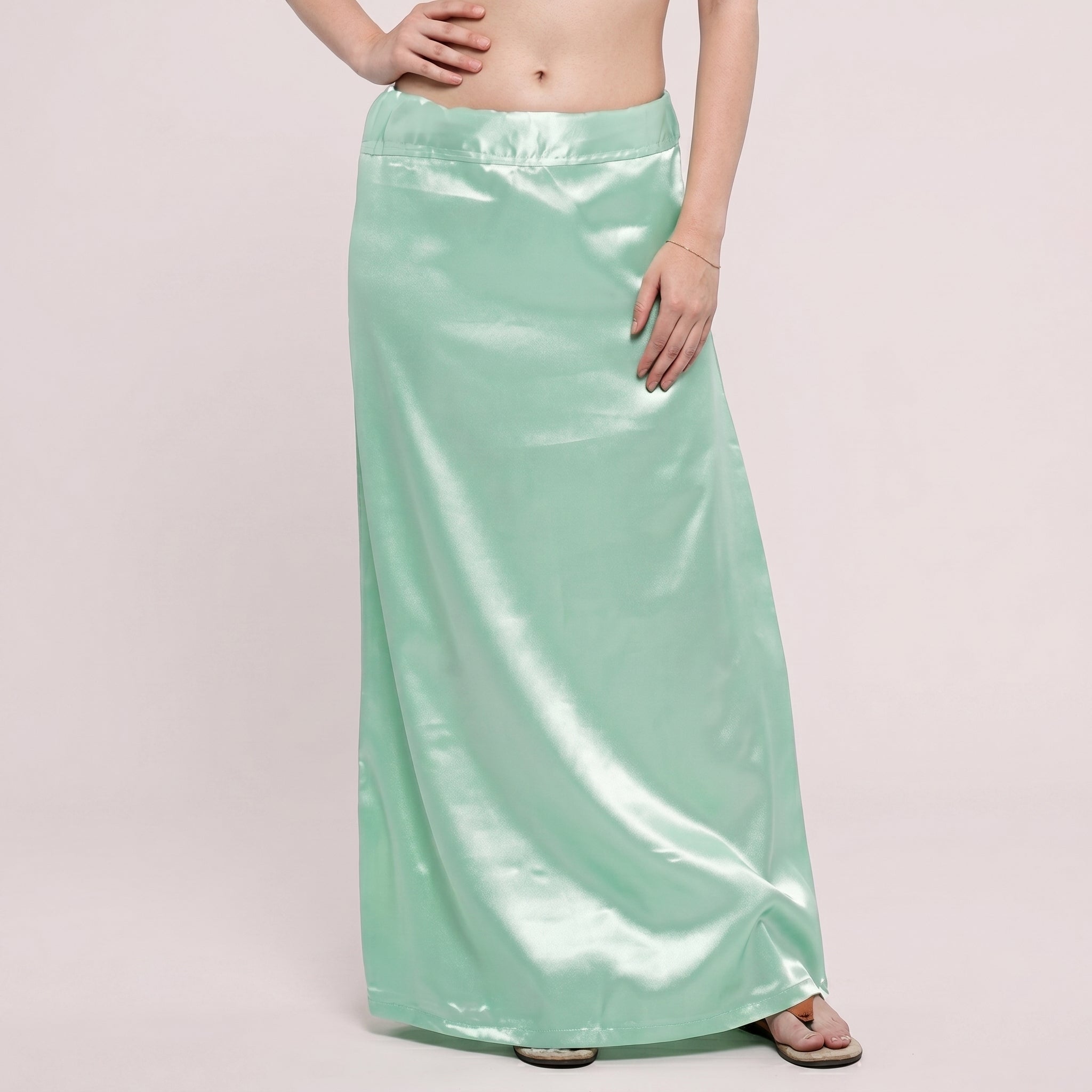Person wearing a light green satin skirt on a plain background