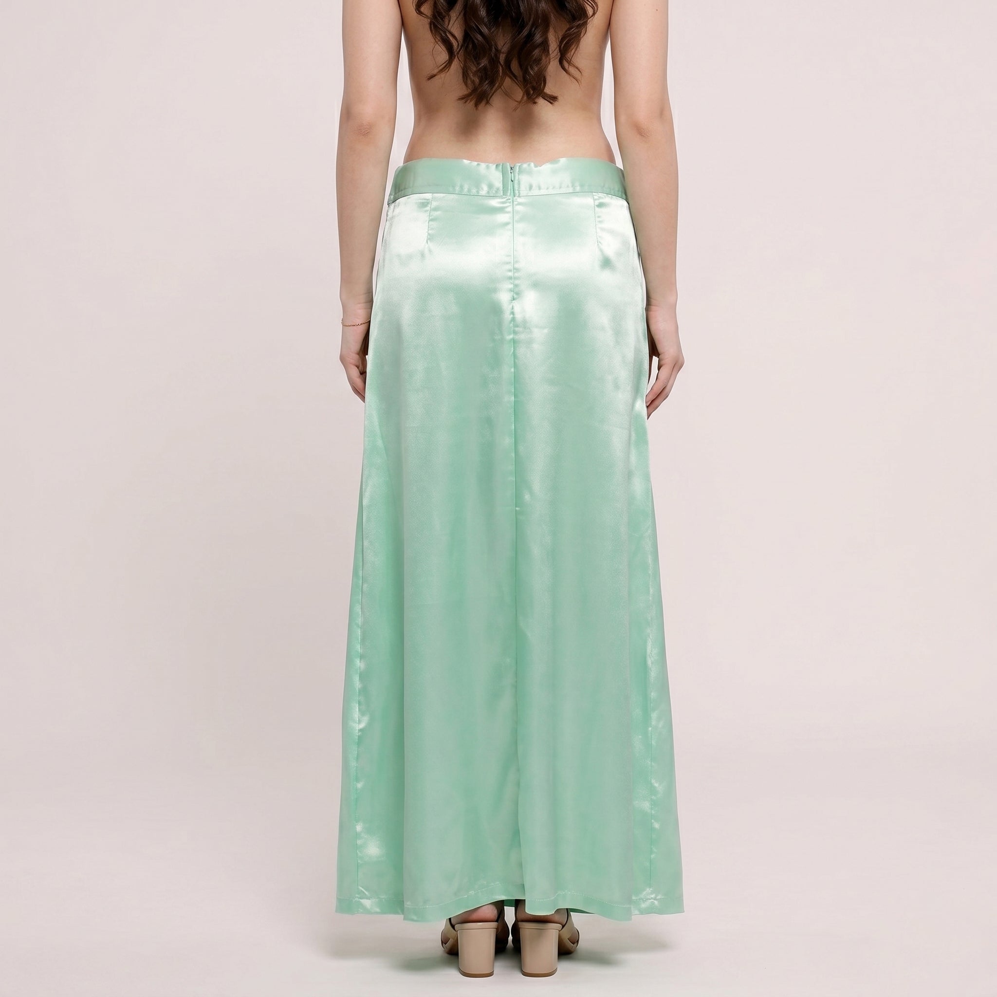 Person wearing a long light green skirt on a plain background