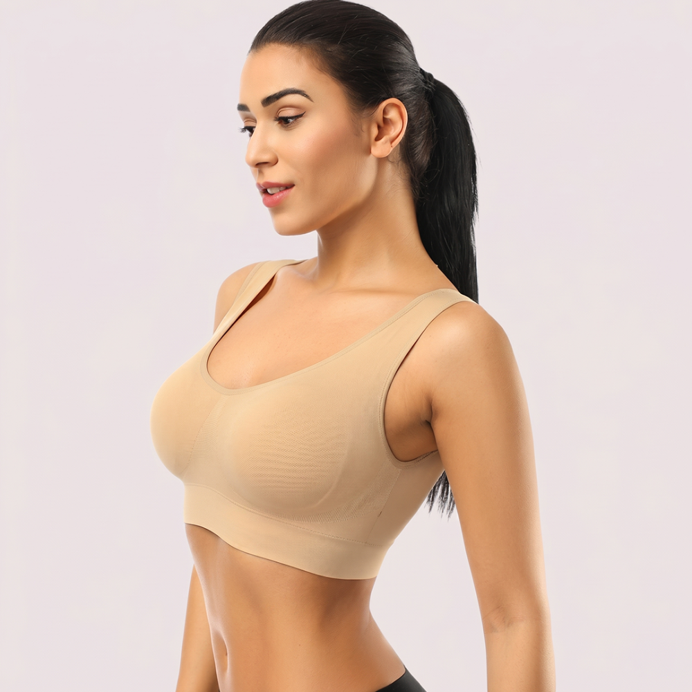 Woman wearing a beige sports bra on a light pink background