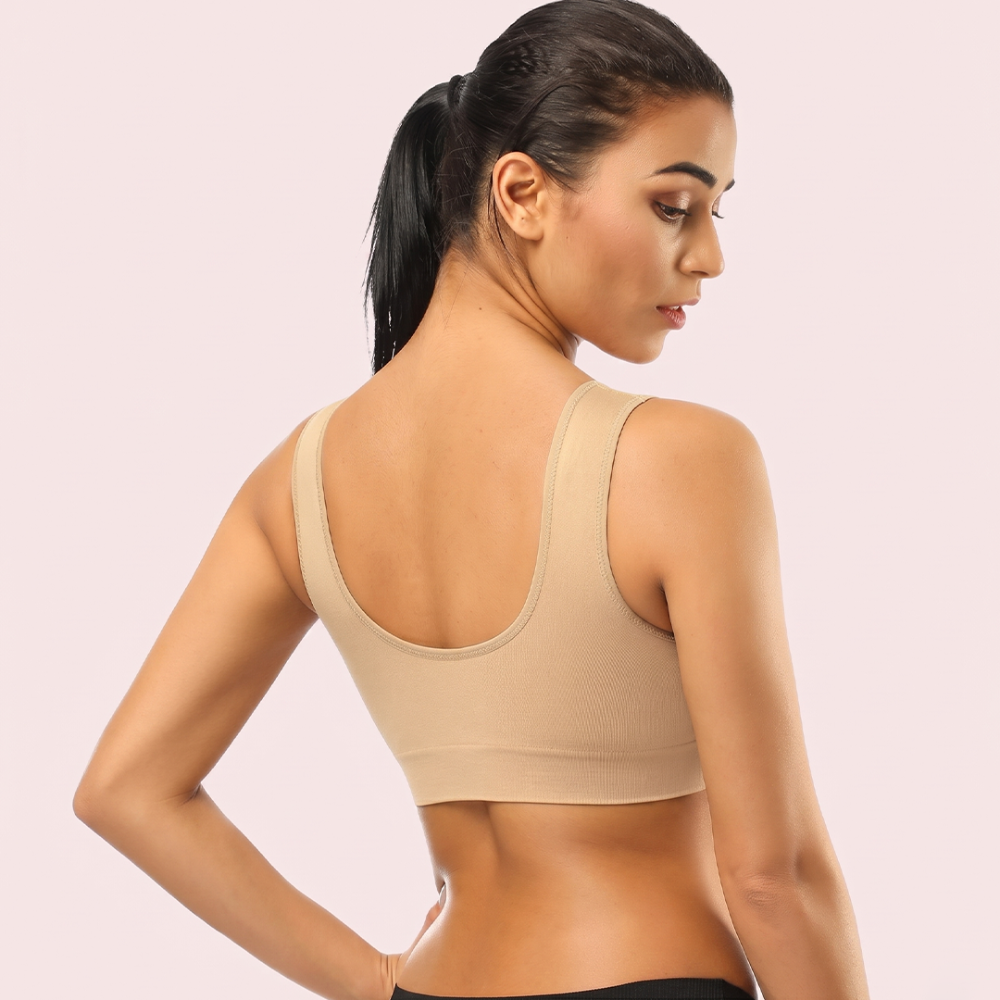 Woman wearing a beige sports bra against a light pink background