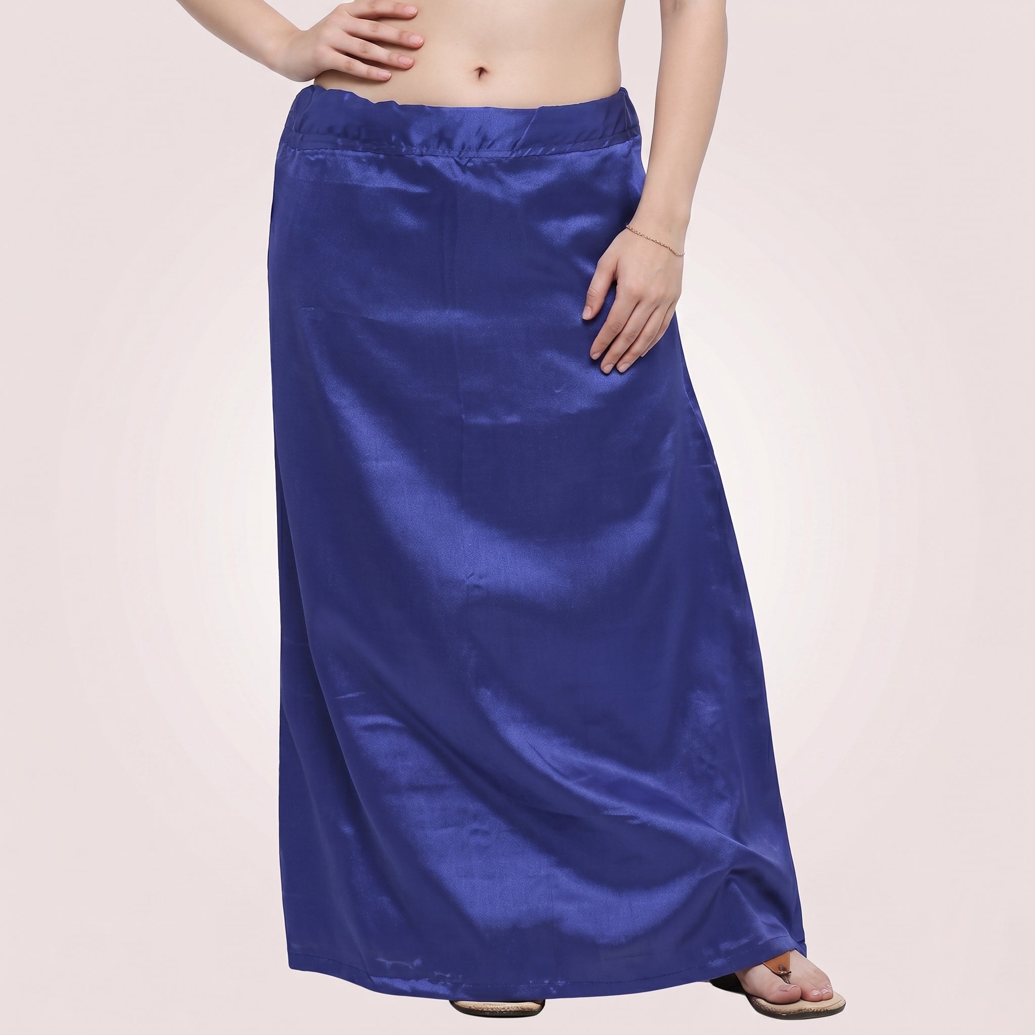 Person wearing a long blue satin skirt on a plain background