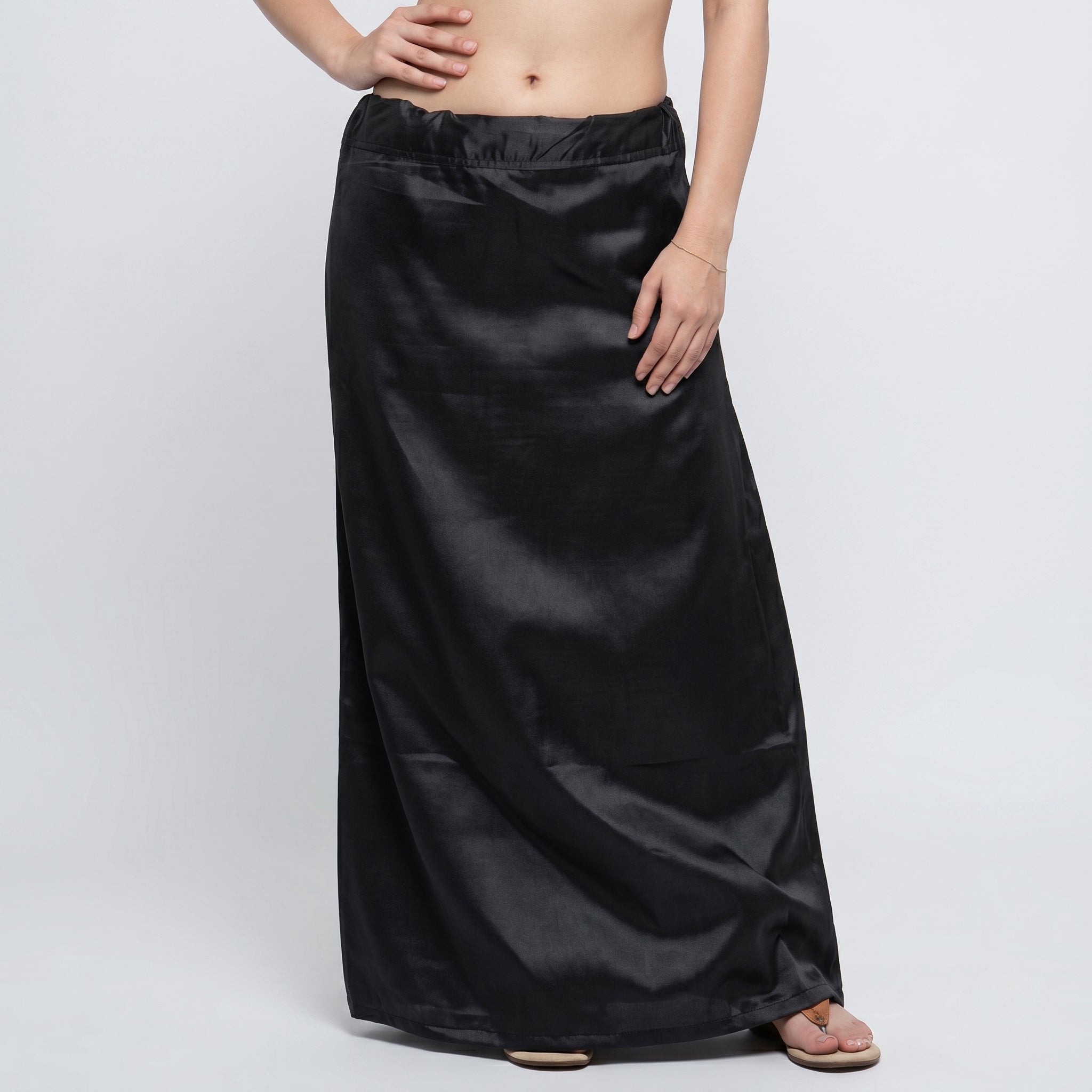 Black satin skirt worn by a person on a white background