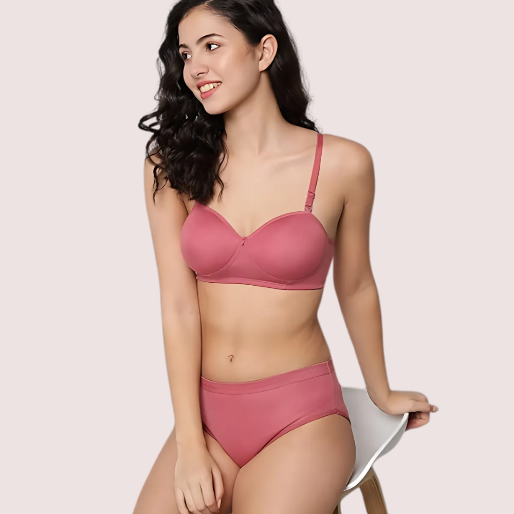 Woman wearing a pink bra and underwear set on a plain background