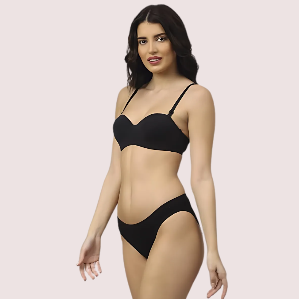 Woman wearing a black bikini set on a light pink background
