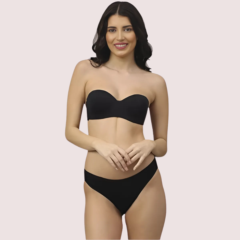 Woman wearing a black strapless bikini against a plain background