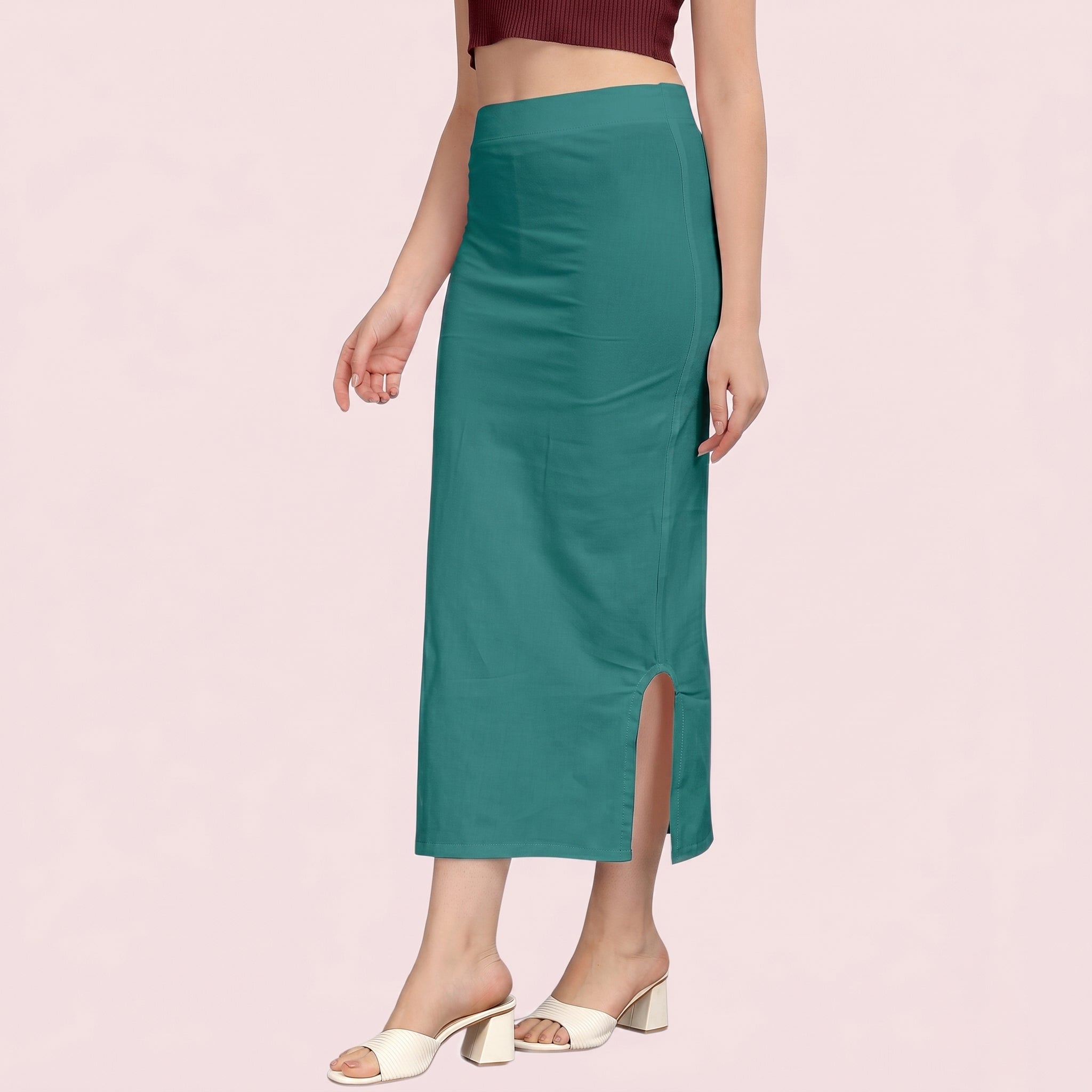 Teal slip skirt worn by a person on a light pink background