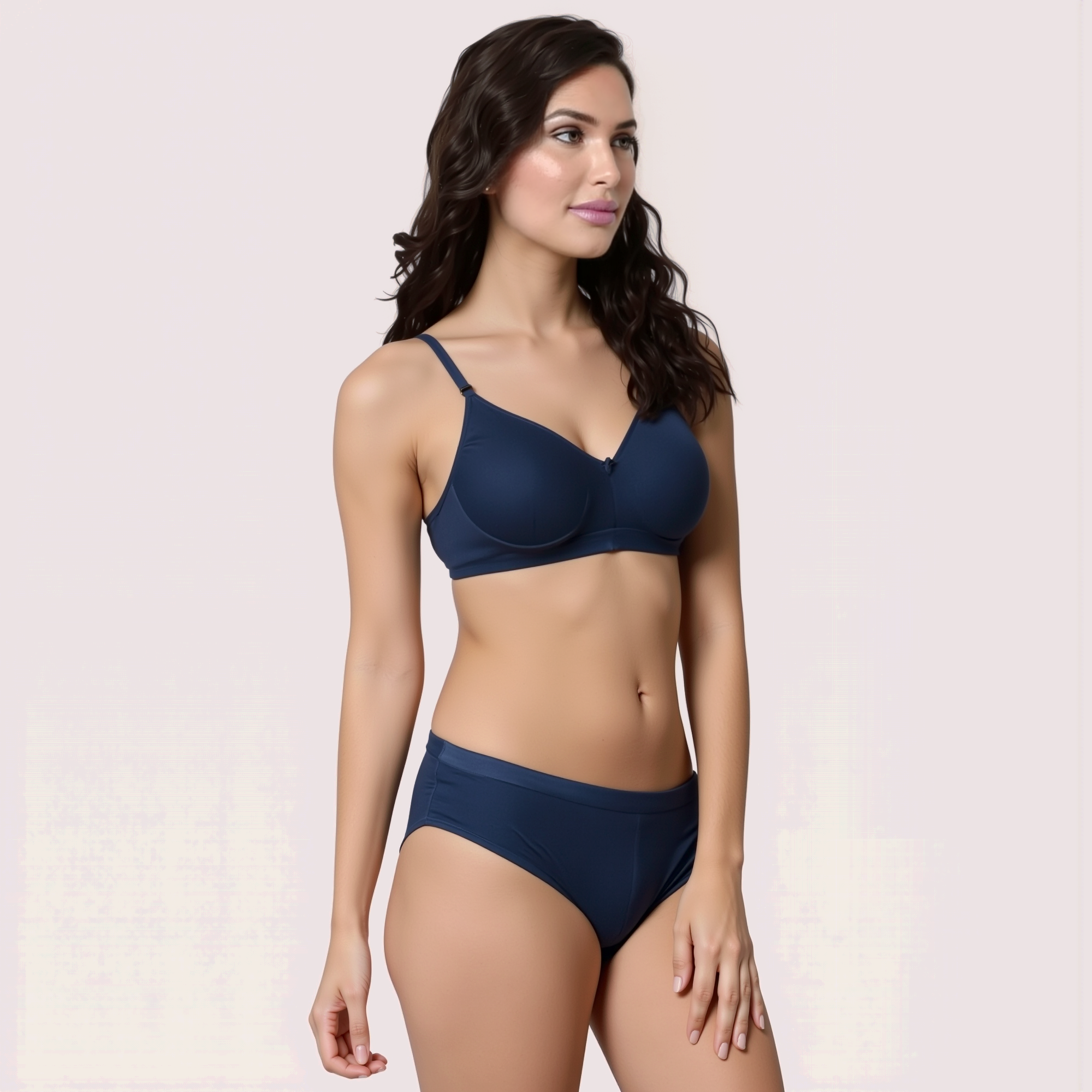Woman wearing a navy blue bikini set on a light pink background