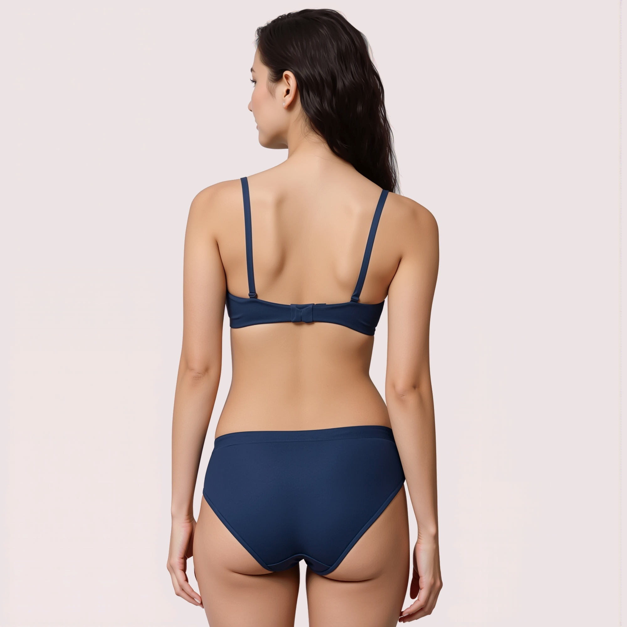 Woman wearing a navy blue bikini on a light pink background