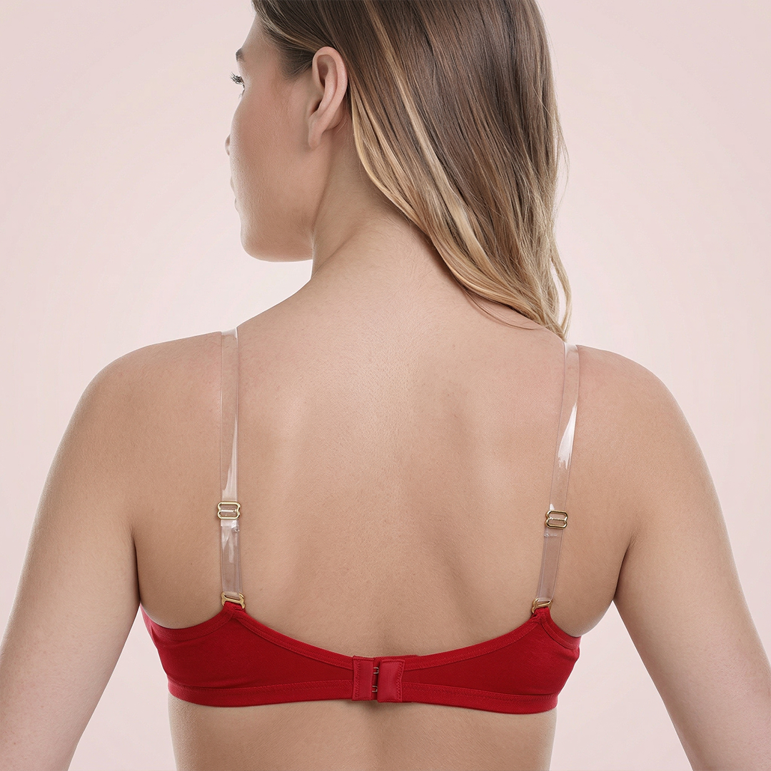 Woman wearing a red bralette with thin straps on a beige background