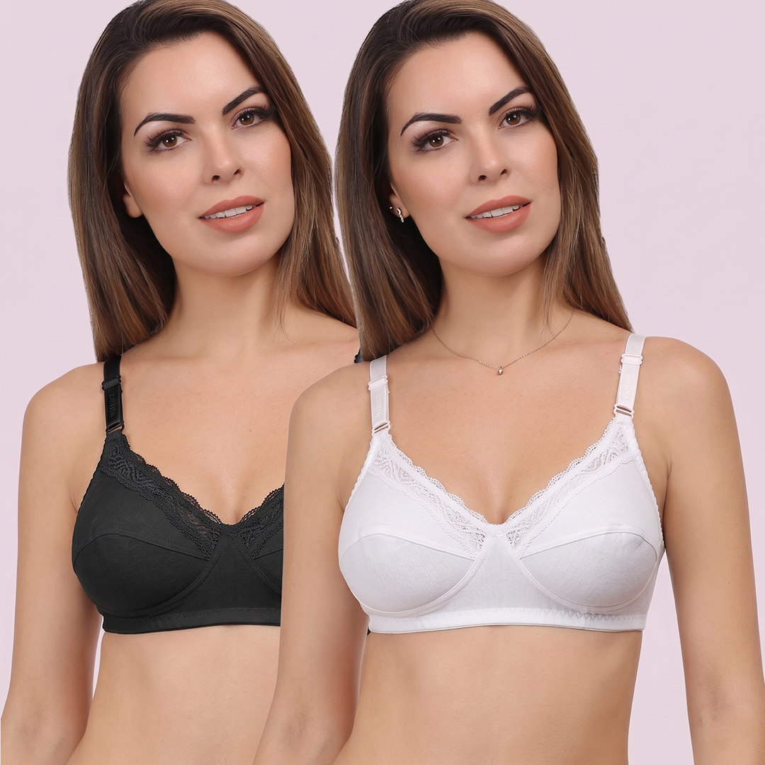 Two women wearing black and white bras on a light pink background