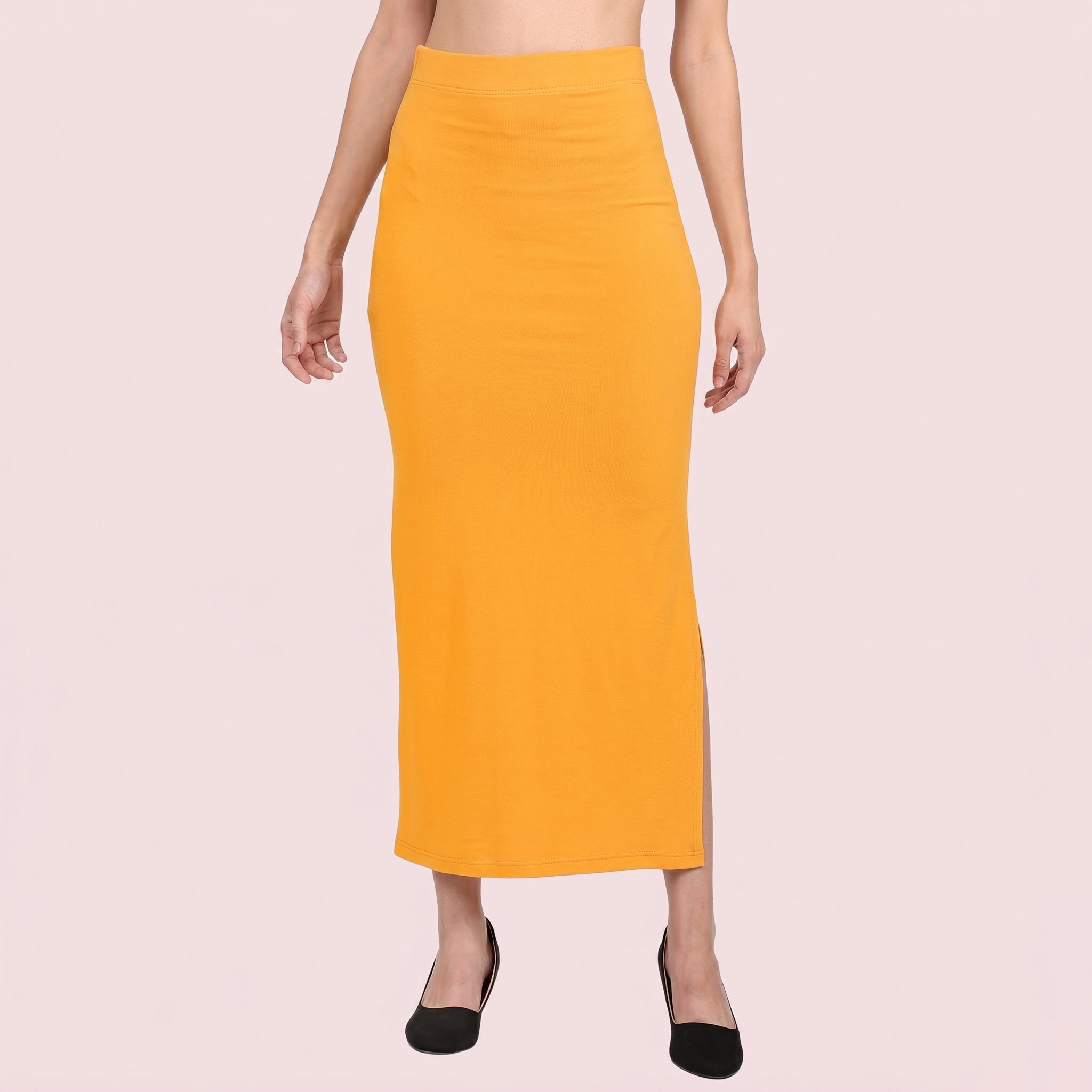 Person wearing a mustard yellow pencil skirt on a light pink background