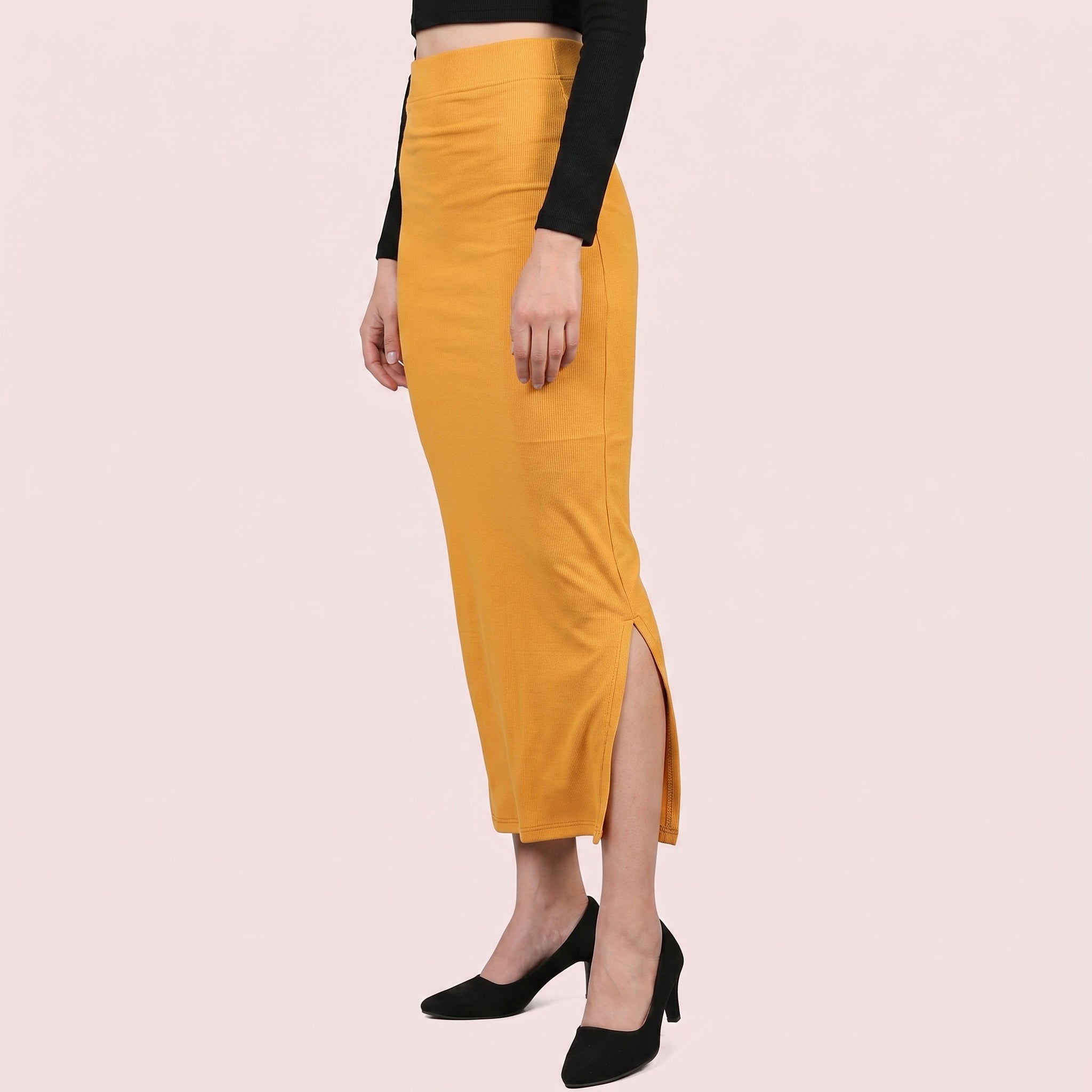 Person wearing a mustard yellow skirt with a black top on a light pink background