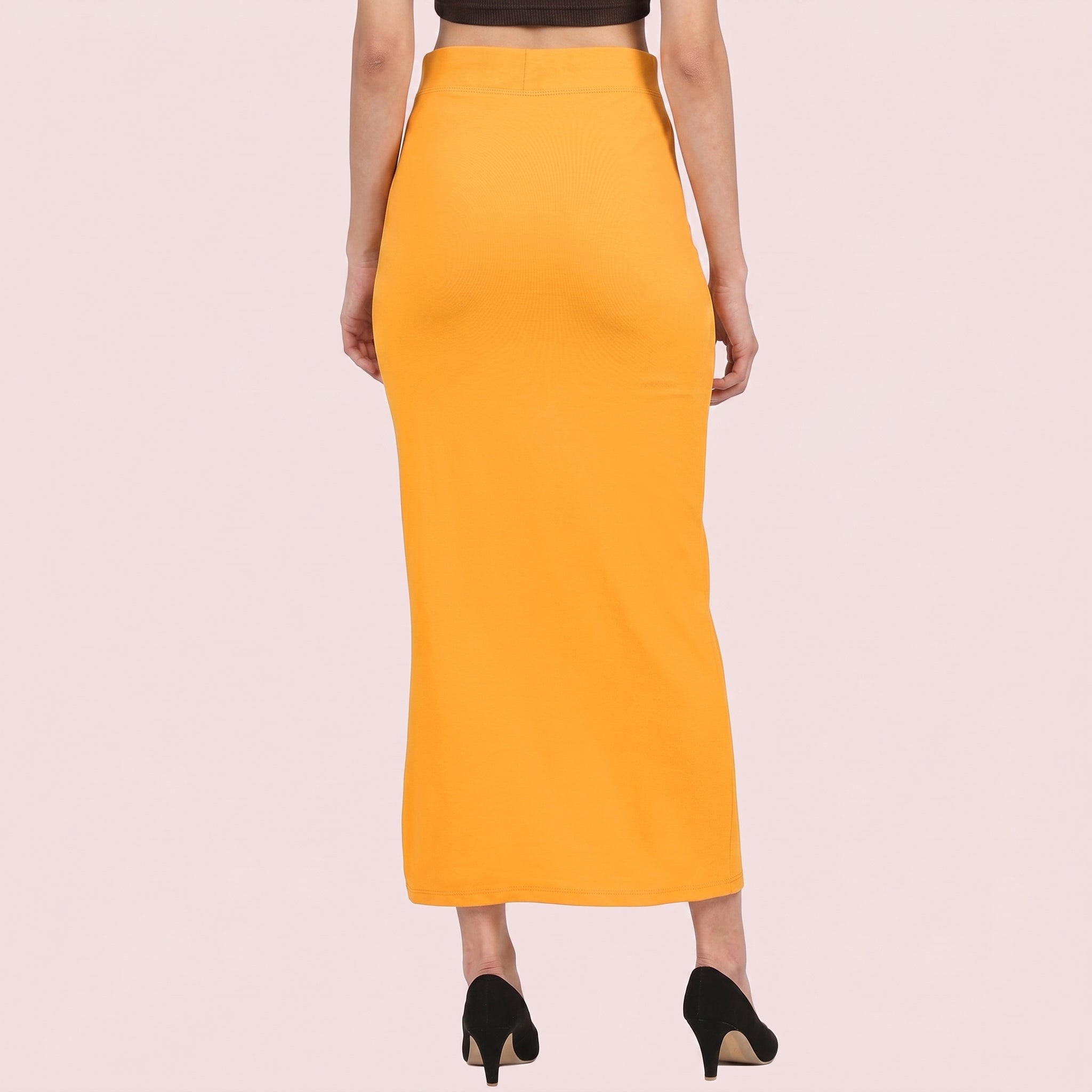 Person wearing a mustard yellow pencil skirt on a light pink background