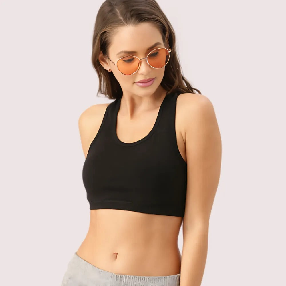 Woman wearing a black sports bra and sunglasses on a light pink background
