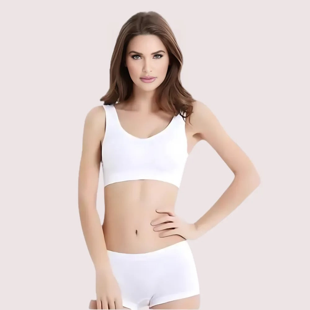 Woman wearing a white sports bra and shorts on a light pink background
